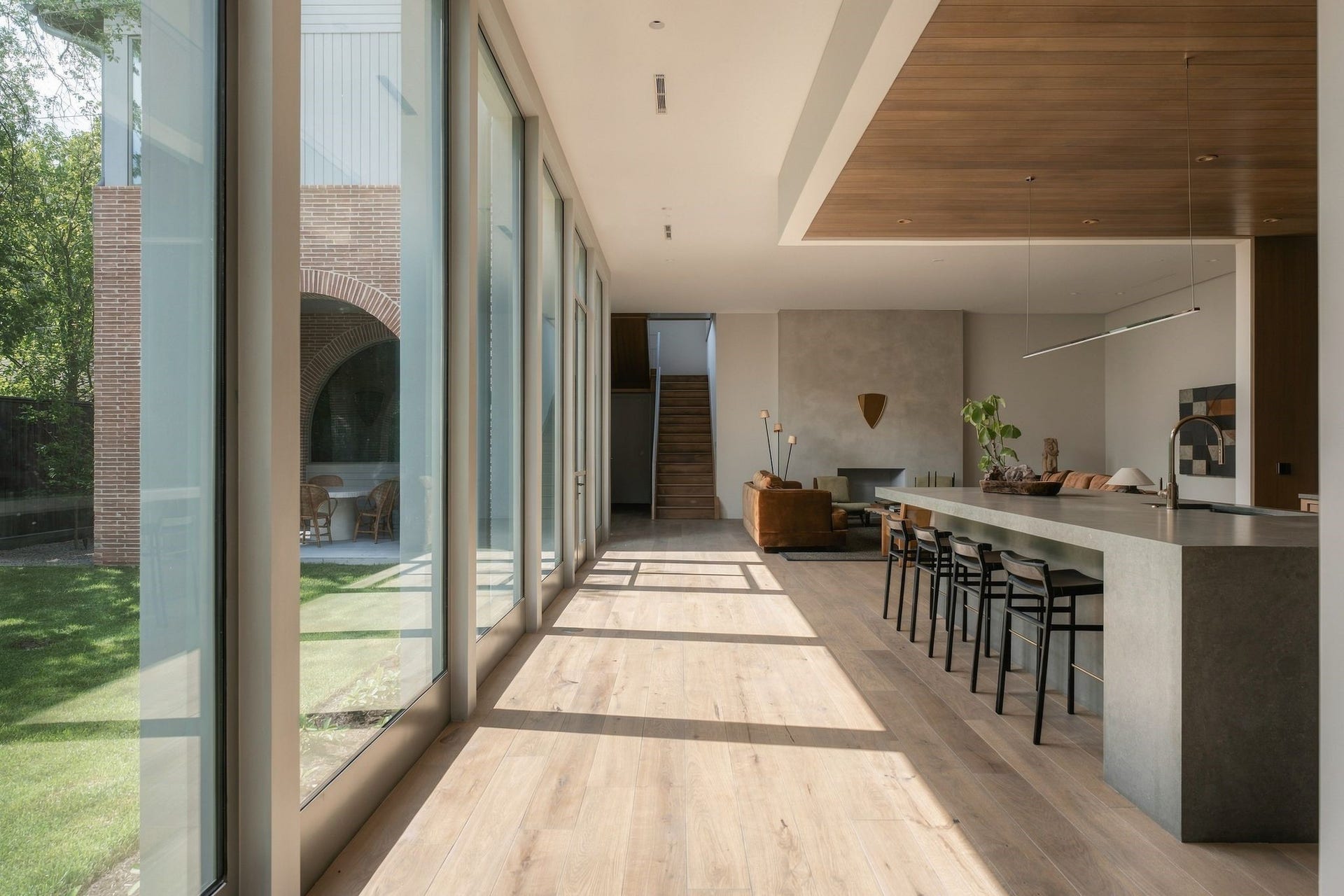 A continuation of the procession, w/a dramatic wall of glass running alongside the backyard as the kitchen opens to the family room beyond. European white oak floors, trimless detailing & carefully framed views create a continuous connection between architecture & landscape.