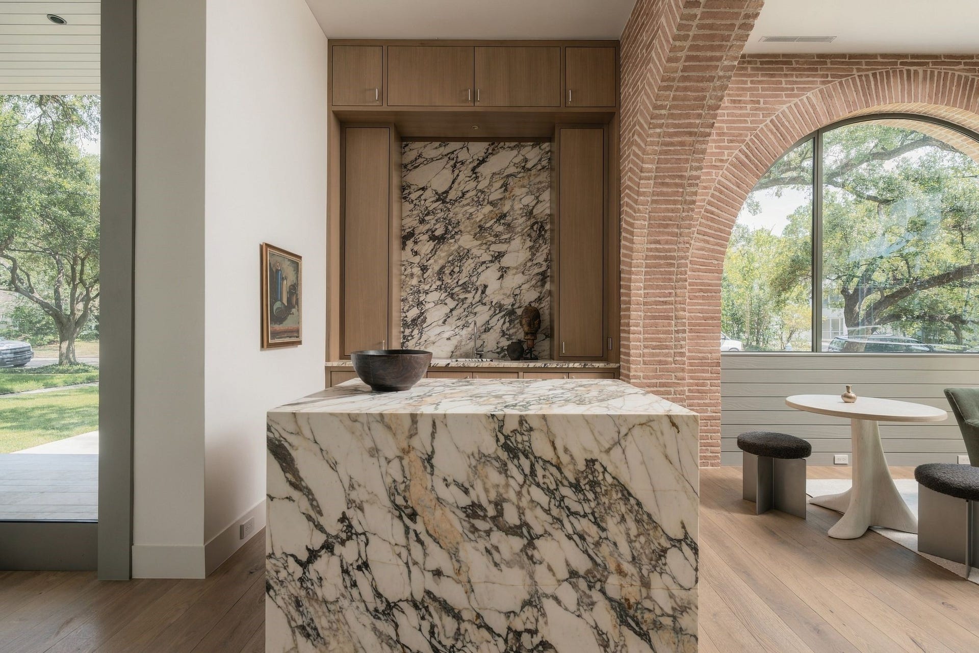 A jewel-box wet bar wrapped in richly veined honed Calacatta Monet, extending seamlessly across the countertops & backsplash for a sculptural statement. Custom rift white oak cabinetry, polished fixtures & two hidden beverage drawers pair beautifully w/the arched view into the parlour beyond.