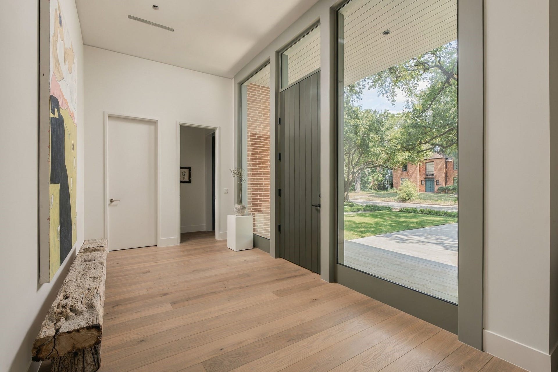 Another perspective of the formal entry highlights the clean architectural detailing & functionality tucked seamlessly into the design. A coat closet provides practical storage, while the powder room sits just opposite. European white oak floors & refined sight lines continue toward the entertaining spaces beyond.