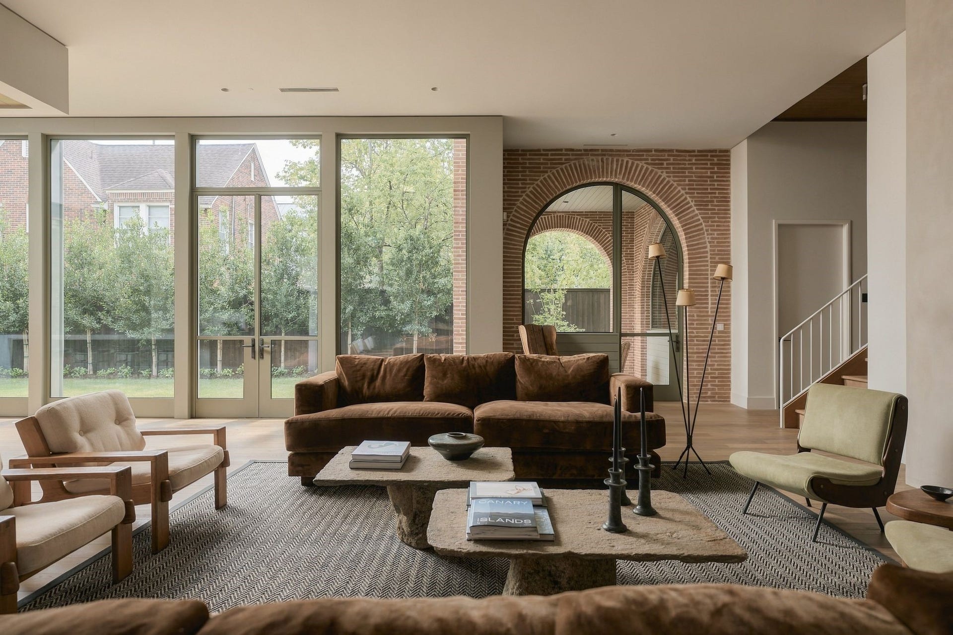A beautifully framed view from the family room toward the backyard. The arched opening creates a natural transition to the covered porch, while expansive glass fills the room w/light & reinforces the repeating arch motif inspired by the architecture of Rice University.