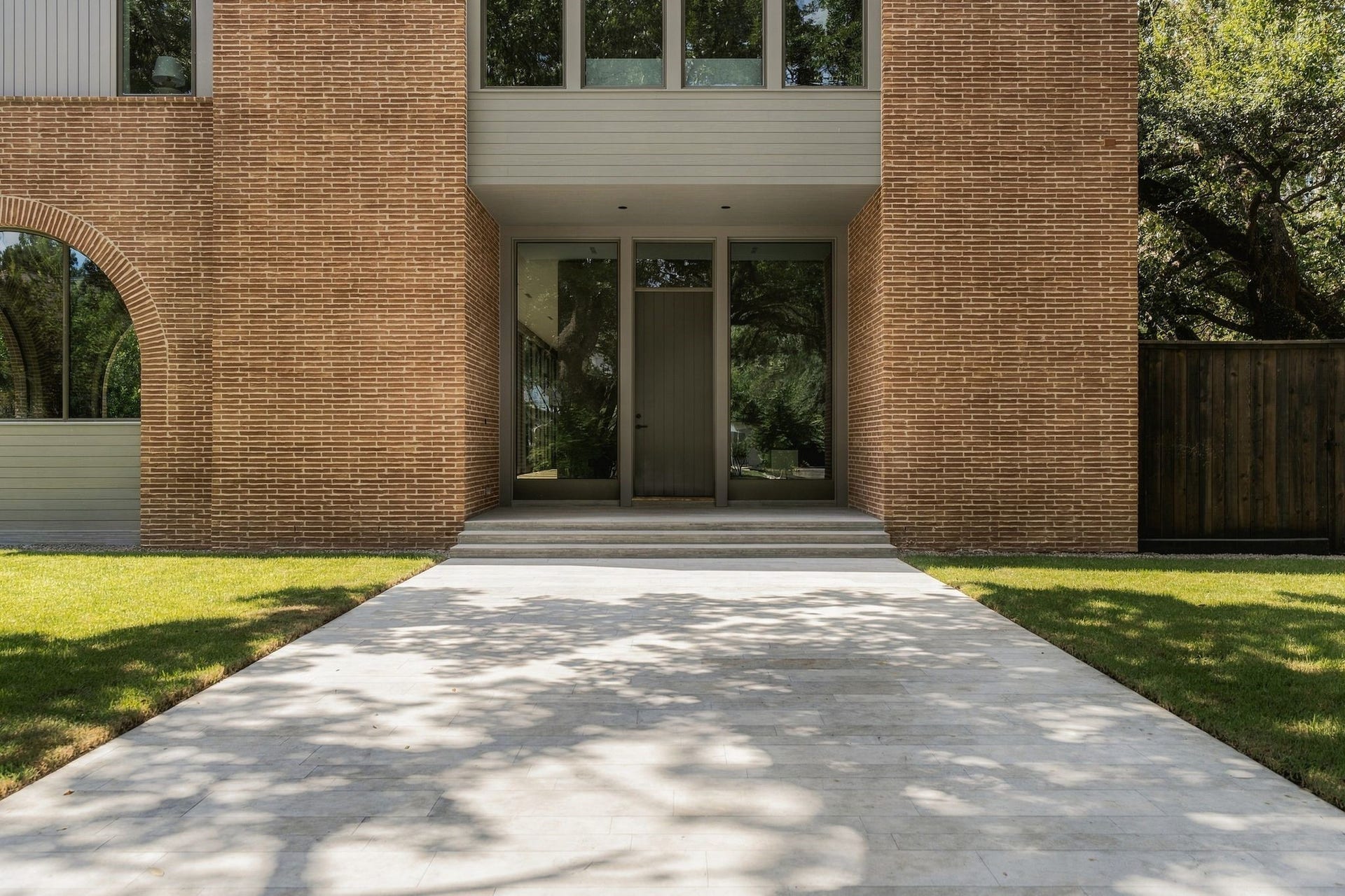 The Rice-inspired arches introduce an architectural motif carried throughout the home. A custom Accoya wood front door was uniquely built within a steel frame & jamb for a streamlined profile, flanked by glass panels that offer the first glimpse into the thoughtful sight lines beyond.