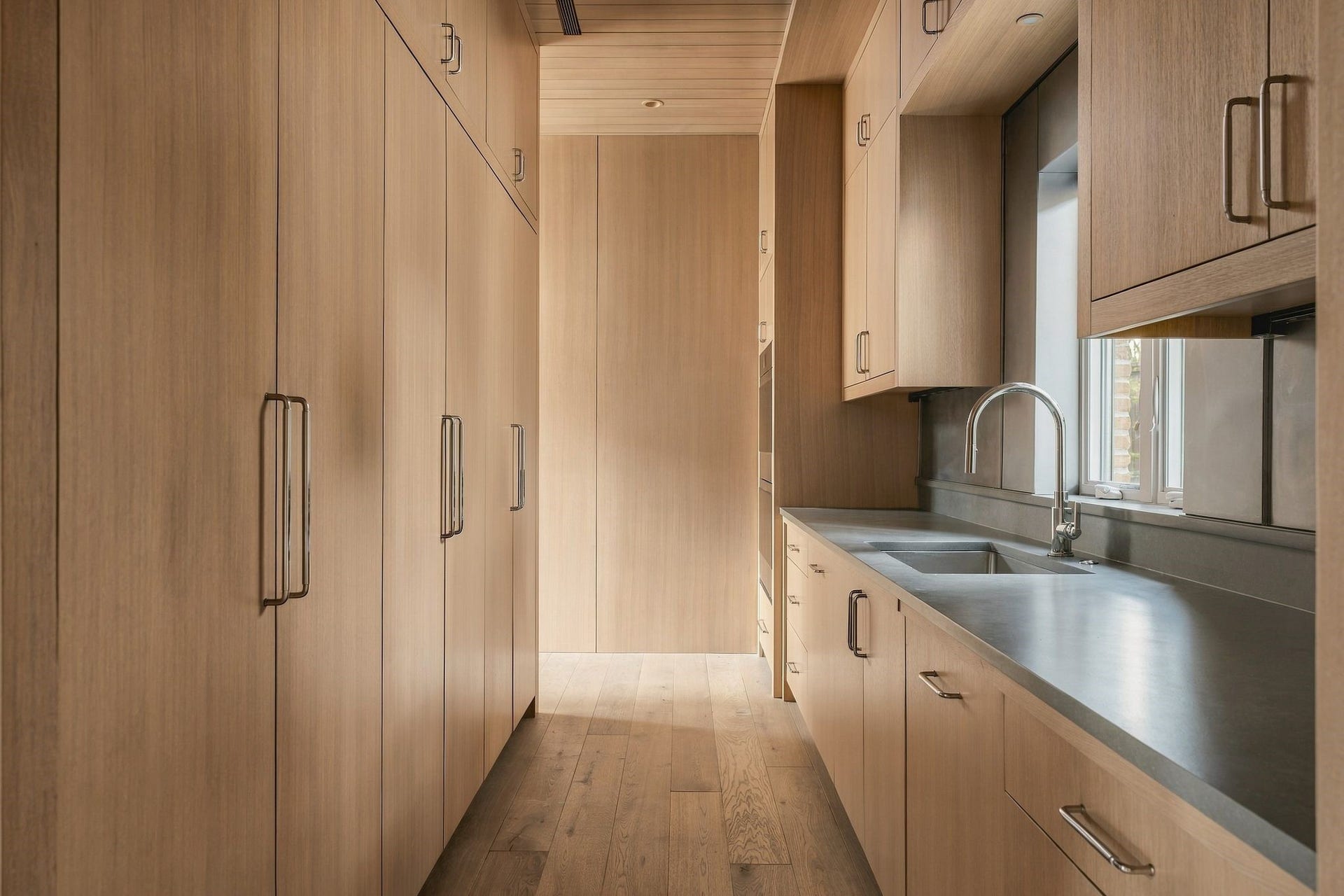 Tucked just beyond the main kitchen, the scullery offers exceptional prep & storage space w/a second single-basin sink, panel-front Bosch dishwasher, double Wolf convection ovens & extensive rift white oak cabinetry/pantry storage. Dual access creates easy service between the kitchen & formal dining.