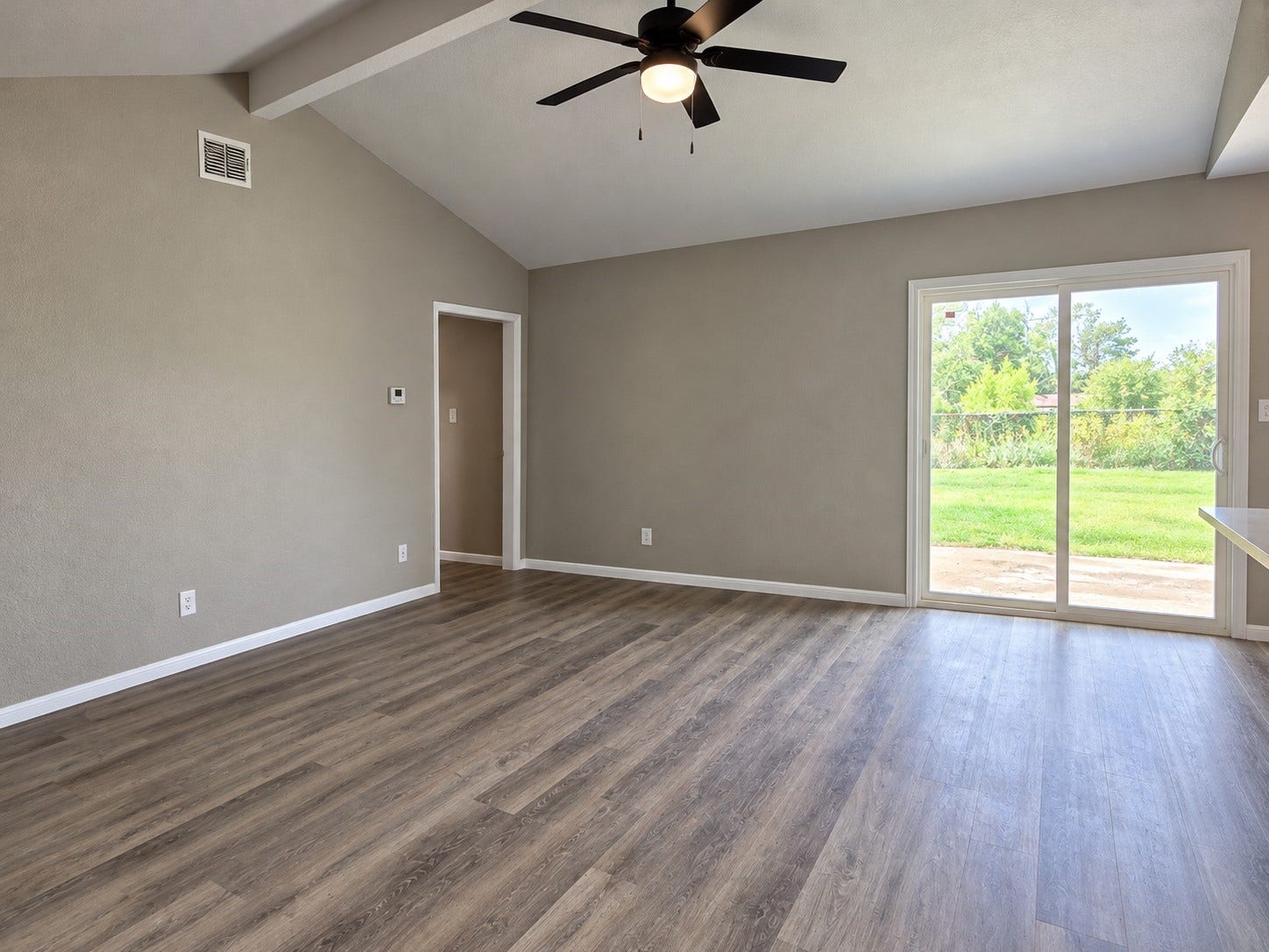 High Vaulted celing in the living room with new ceiling fans and a new sliding glass door opening to the back patio,