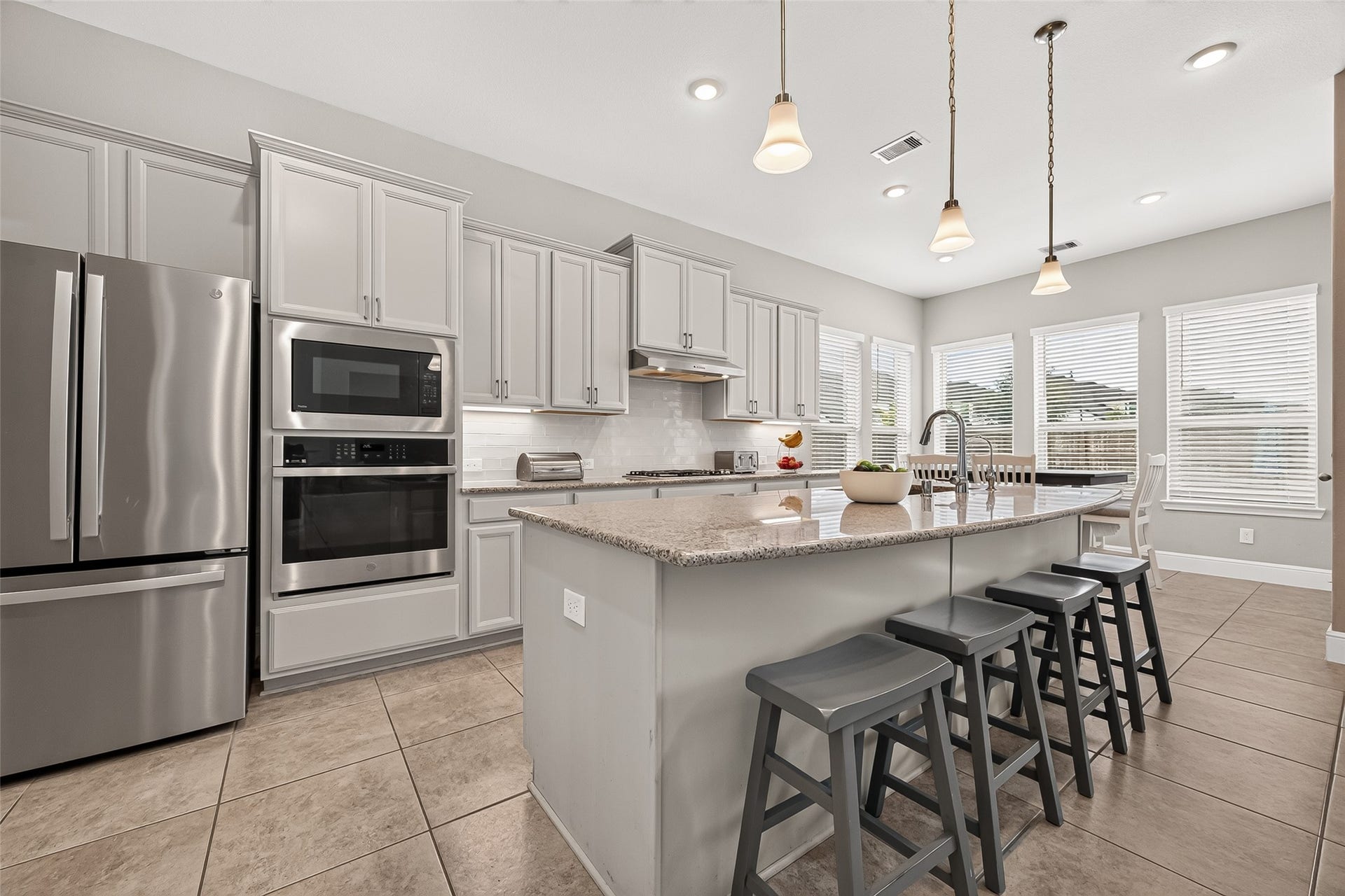 Island with breakfast bar seating and pendant lighting.
