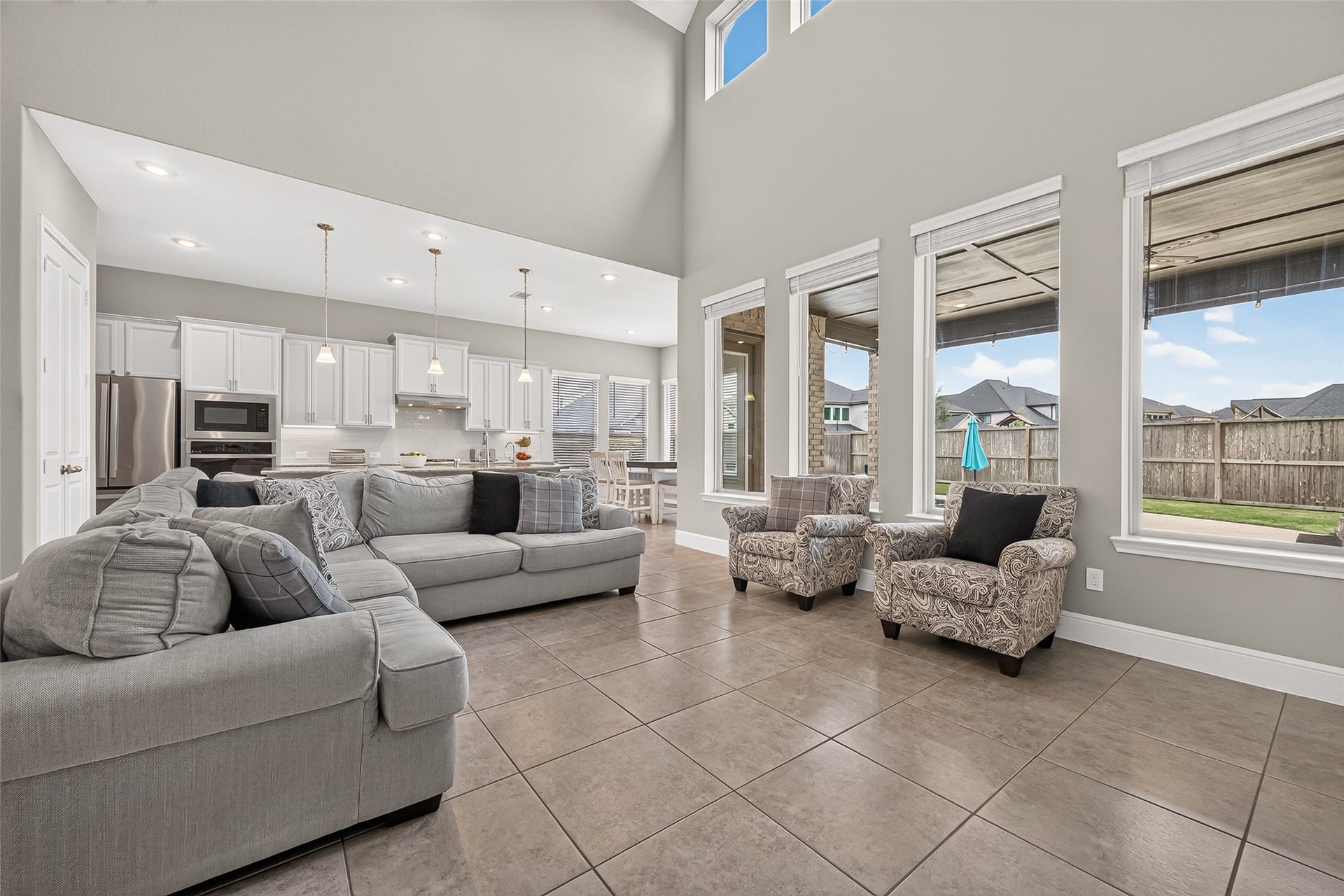 Living room on the first floor open to the kitchen and large windows looking out to the back patio and yard.