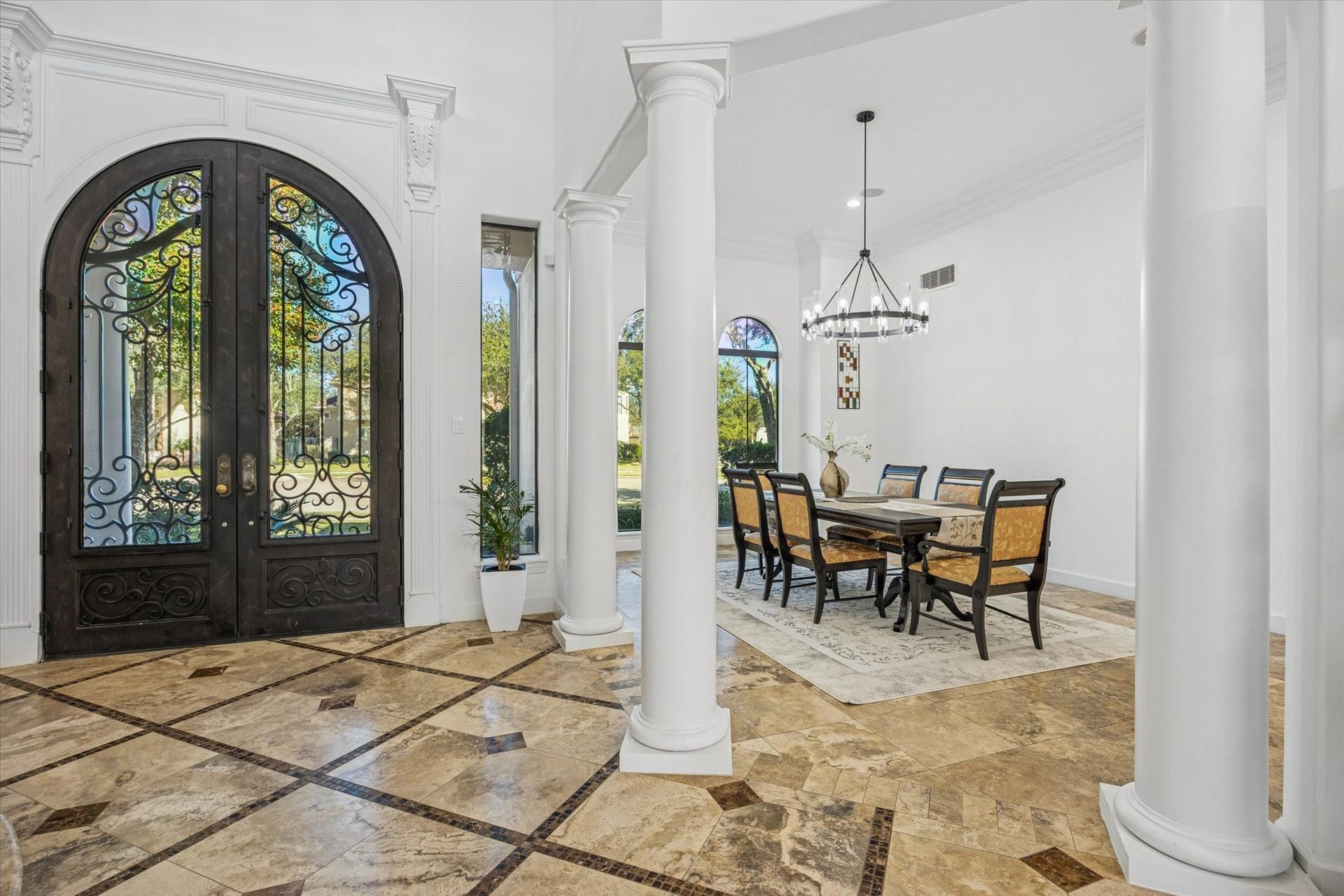 61 Open Sands Court, Sugar Land, TX 77479 Elegant entryway with ornate double doors and a spacious dining area. Features high ceilings, decorative columns, and tile flooring, creating a luxurious and inviting atmosphere.