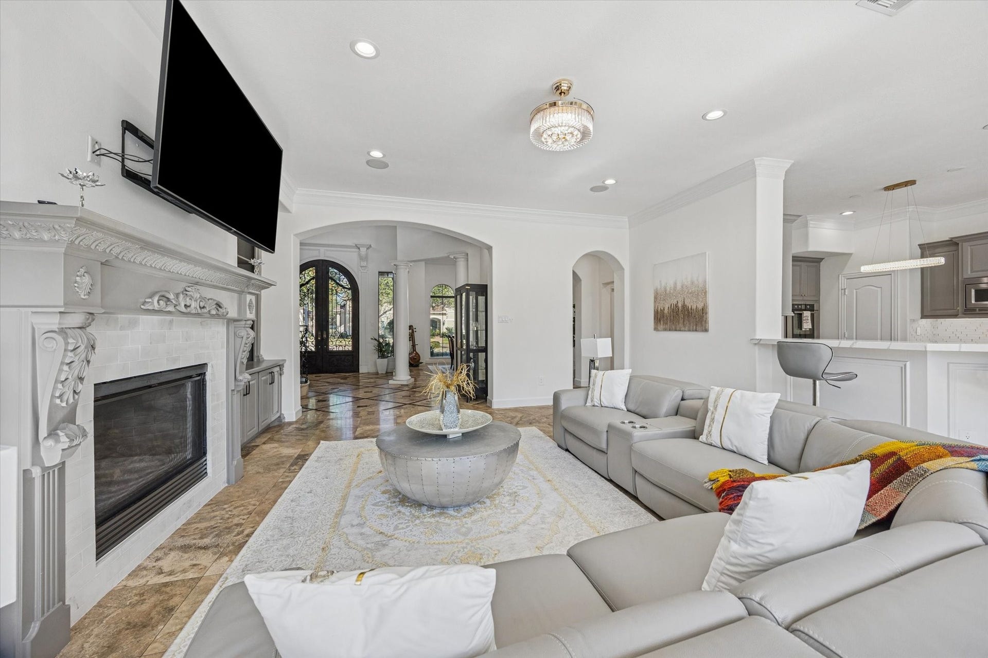 61 Open Sands Court, Sugar Land, TX 77479 This spacious living room features a modern open layout with a cozy fireplace, The room flows seamlessly into the adjoining kitchen area, ideal for entertaining. High ceilings and large windows provide ample natural light.