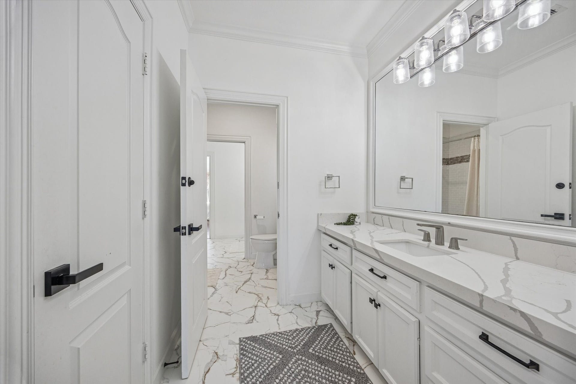 61 Open Sands Court, Sugar Land, TX 77479 One of 2 upstairs adjoining jack and jill bathrooms. Bright and clean bathroom featuring a large mirror, sleek modern fixtures, and a spacious vanity with a quartz countertop.