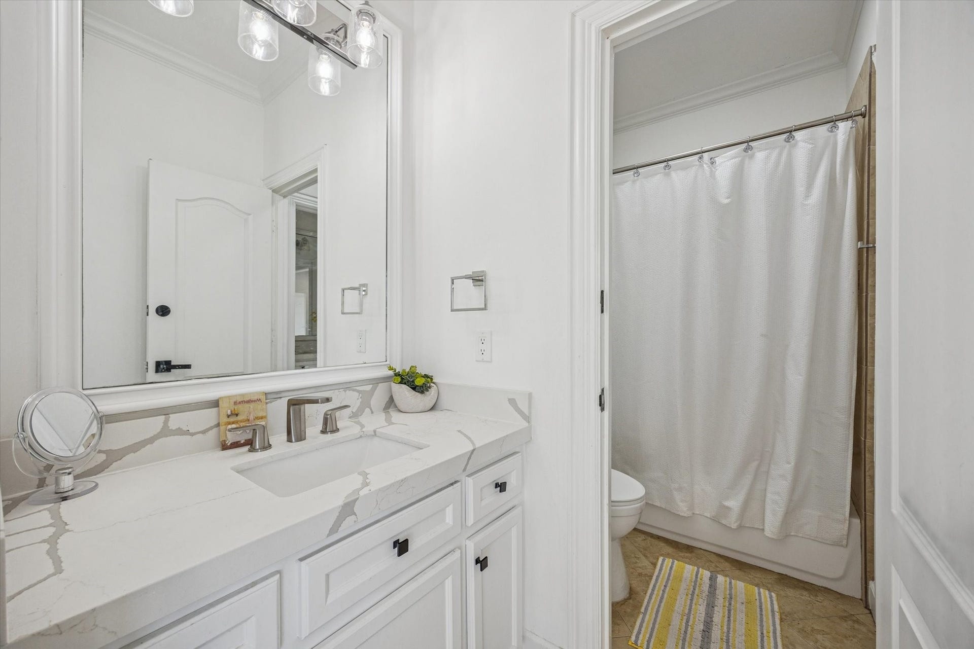 61 Open Sands Court, Sugar Land, TX 77479 One of 2 upstairs adjoining jack and jill bathrooms. Bright and clean bathroom featuring a large mirror, sleek modern fixtures, and a spacious vanity with a quartz countertop.