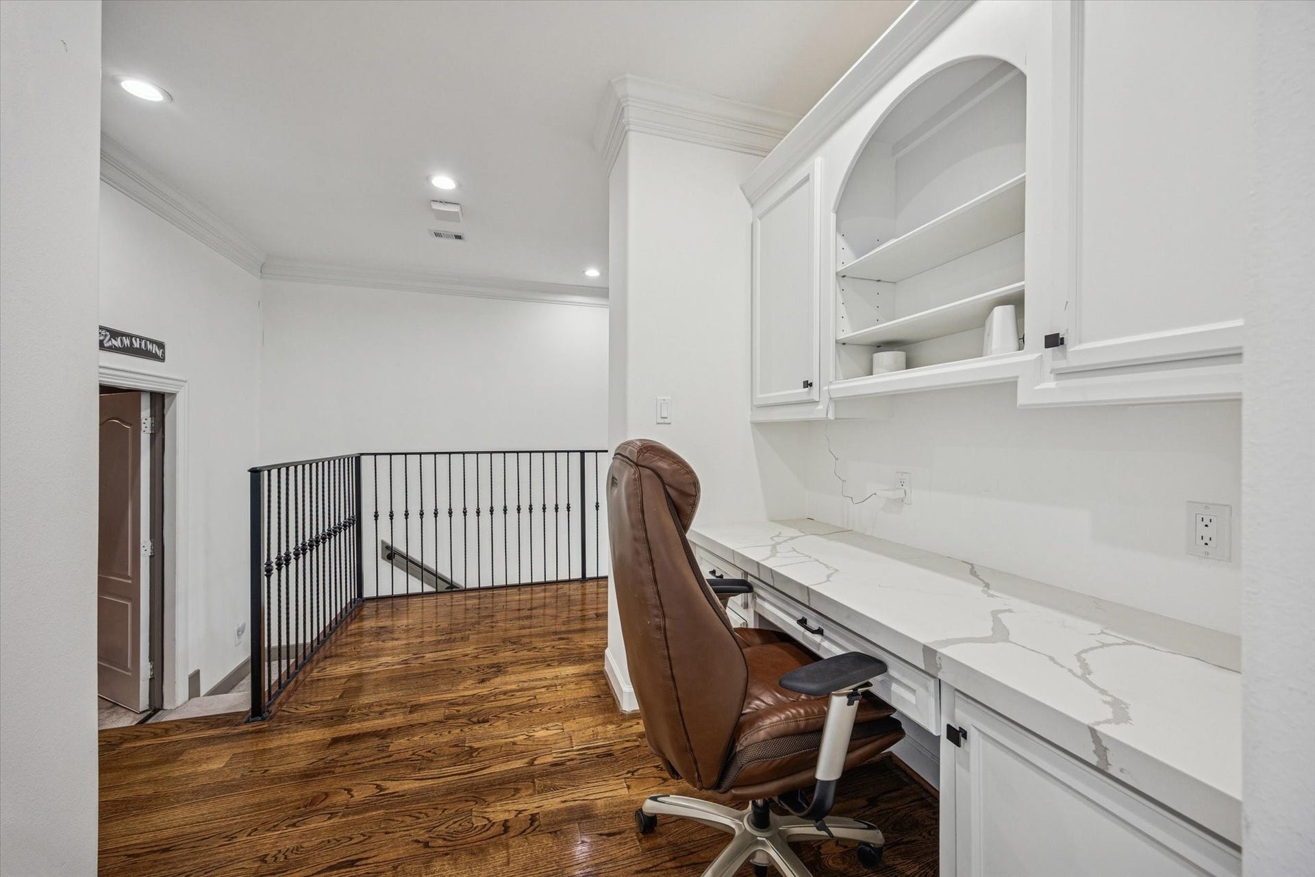 61 Open Sands Court, Sugar Land, TX 77479 This photo shows a cozy home office nook with built-in white cabinetry and a quartz countertop. The space is well-lit with recessed lighting and has warm wooden flooring.
