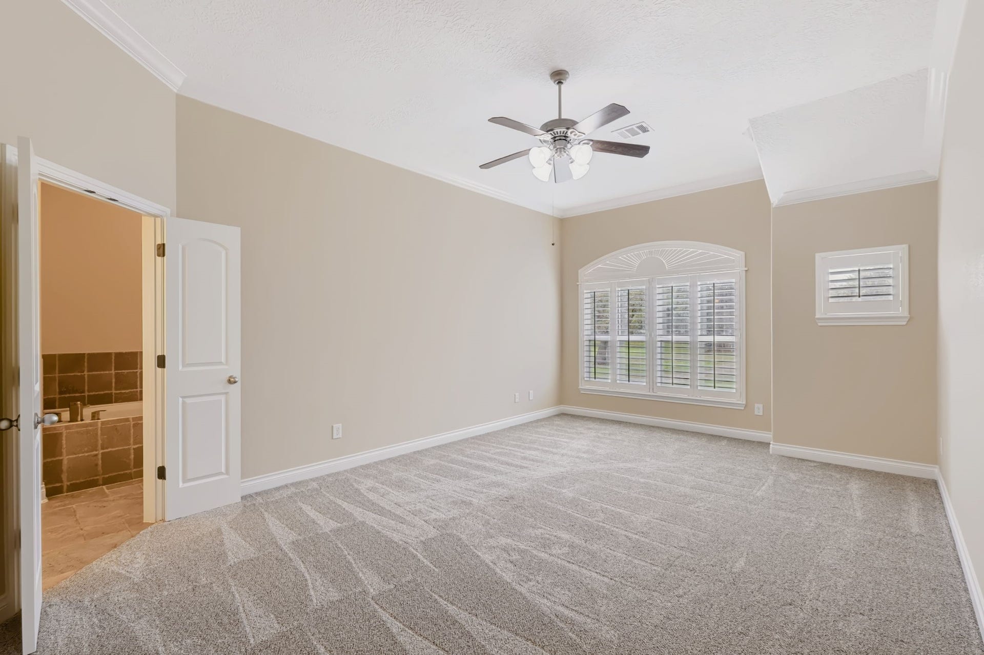 1642 Pultar Road, Richmond, TX 77469 Large primary bedroom with new carpet, ceiling fan, crown molding, shutters and ensuite bathroom.