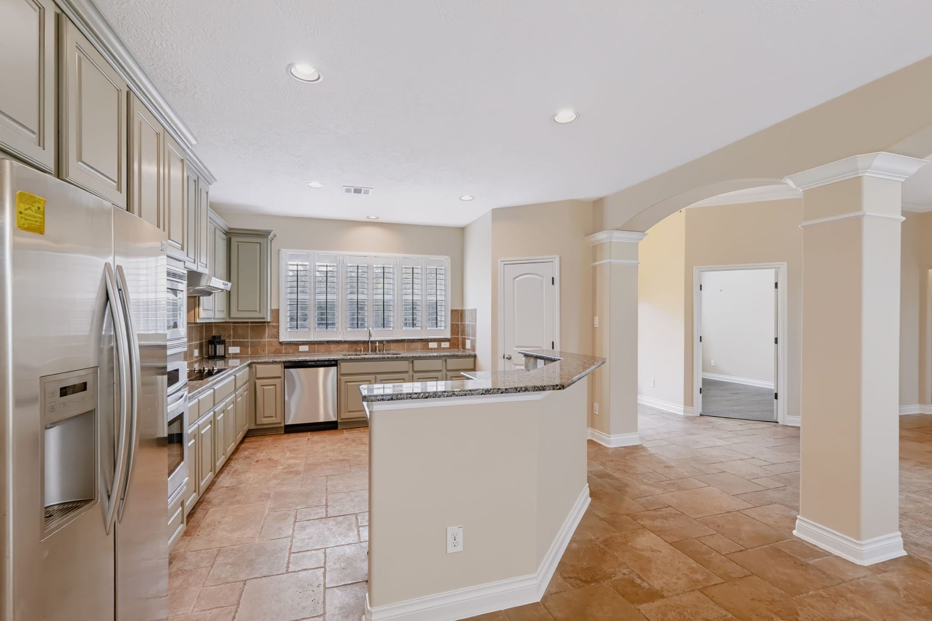 1642 Pultar Road, Richmond, TX 77469 Family room is open to the kitchen and the spaces are defined with subtle arches. Large window over the sink looks out to front yard.
