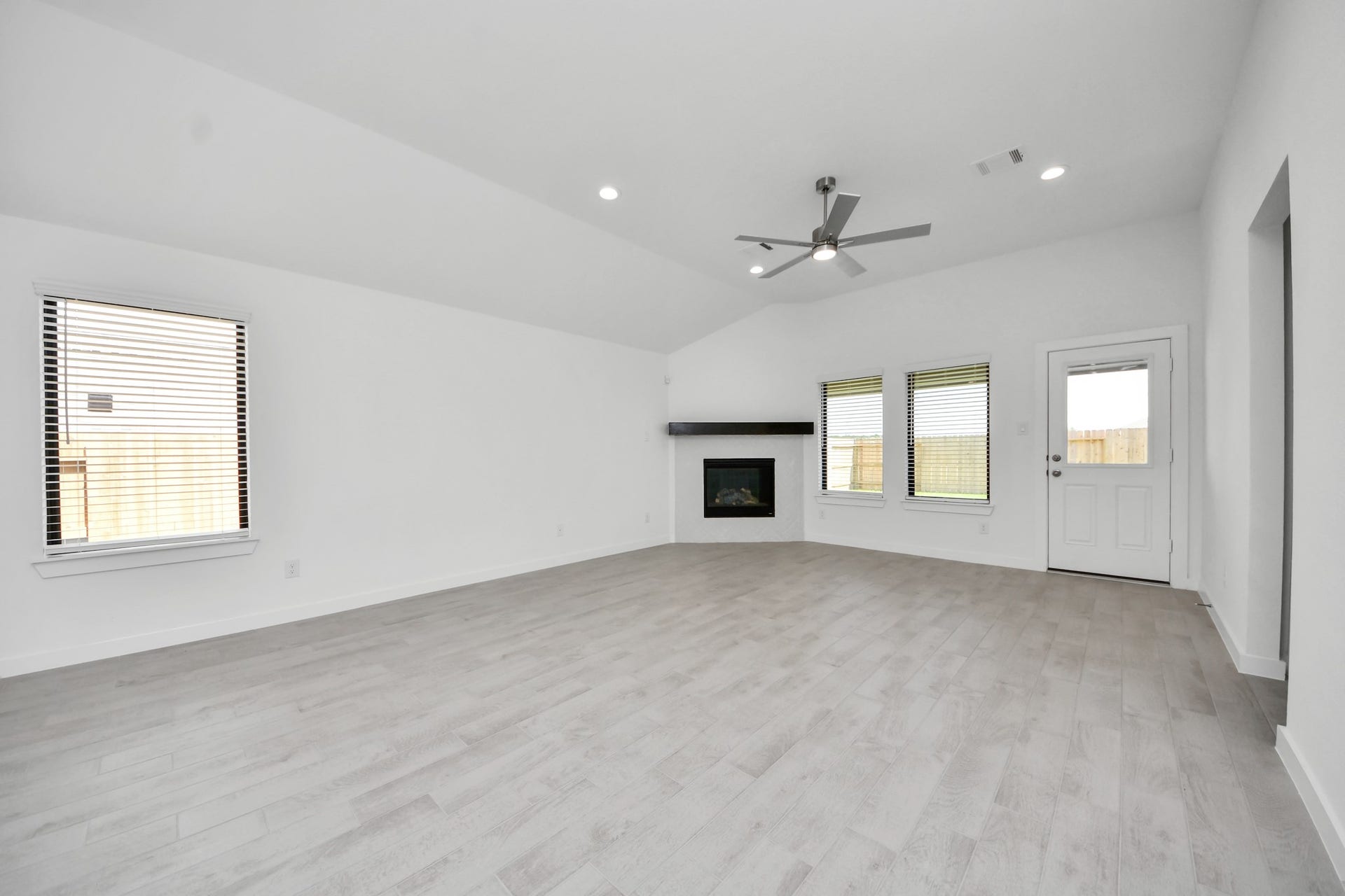 3068 Spoolwood Trail, Magnolia, TX 77355 Family room flooded with natural light through the expansive windows. The premium tile flooring adds a touch of luxury to the space, creating the perfect setting for relaxing moments and cherished gatherings with loved ones