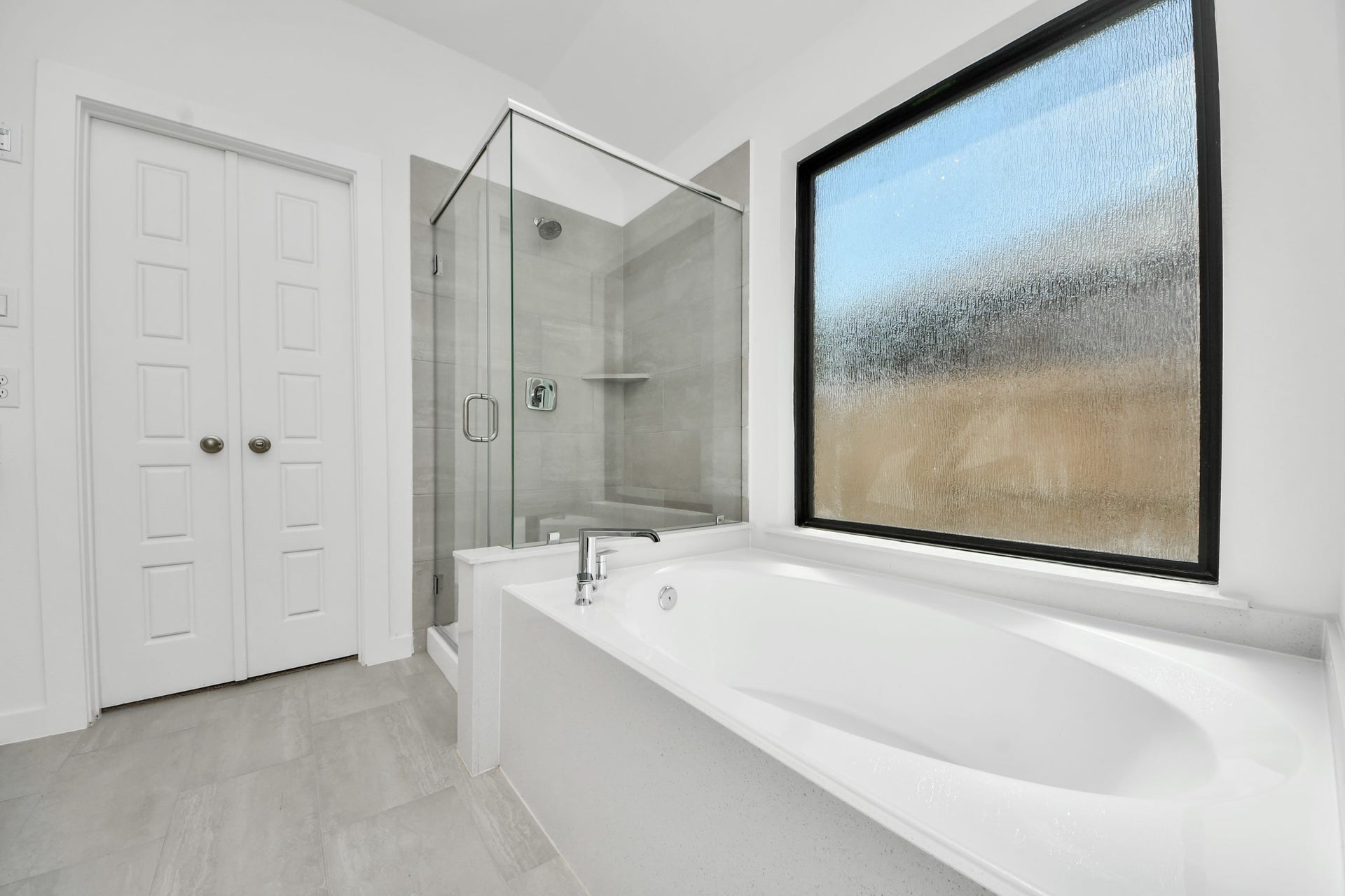 3068 Spoolwood Trail, Magnolia, TX 77355 Escape to a spa-like oasis in this primary bathroom. Enjoy a walk-in shower with tile surround, a separate garden tub with custom detailing, and an elegant vanity featuring light countertops, modern hardware, and beautiful vanity lights. Experience luxury and relaxation in every detail.