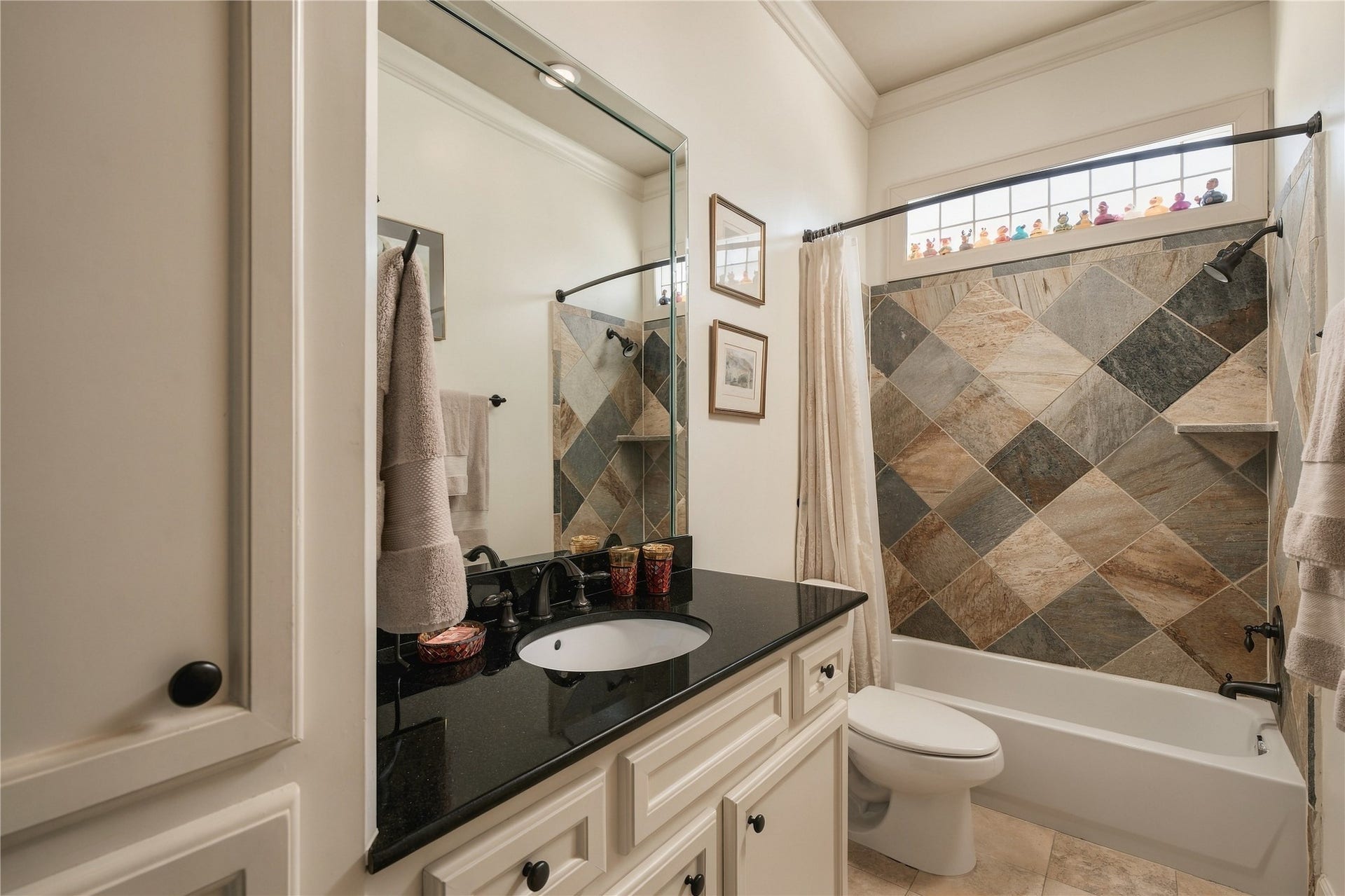 523 Lovett Boulevard, Houston, TX 77006 The adjoining bath brings in a richer material moment, with a granite-topped vanity and patterned stone surrounding the tub and shower.