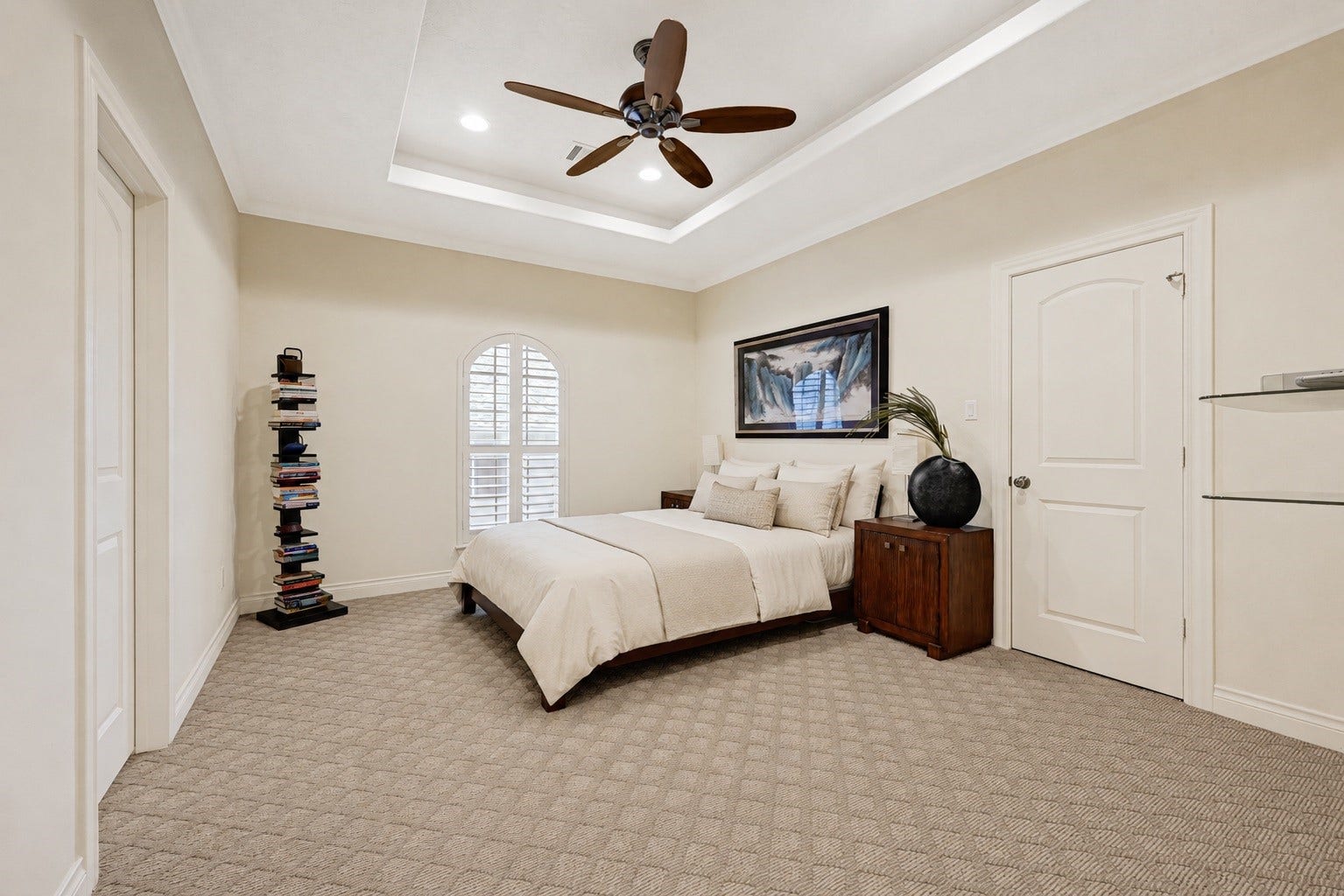 3 Waterford Pointe Circle, Sugar Land, TX 77479 Spacious bedroom with a cozy atmosphere, featuring a stylish tray ceiling, elegant fan, and soft carpeting. Natural light streams through an arched window, complementing the neutral color palette