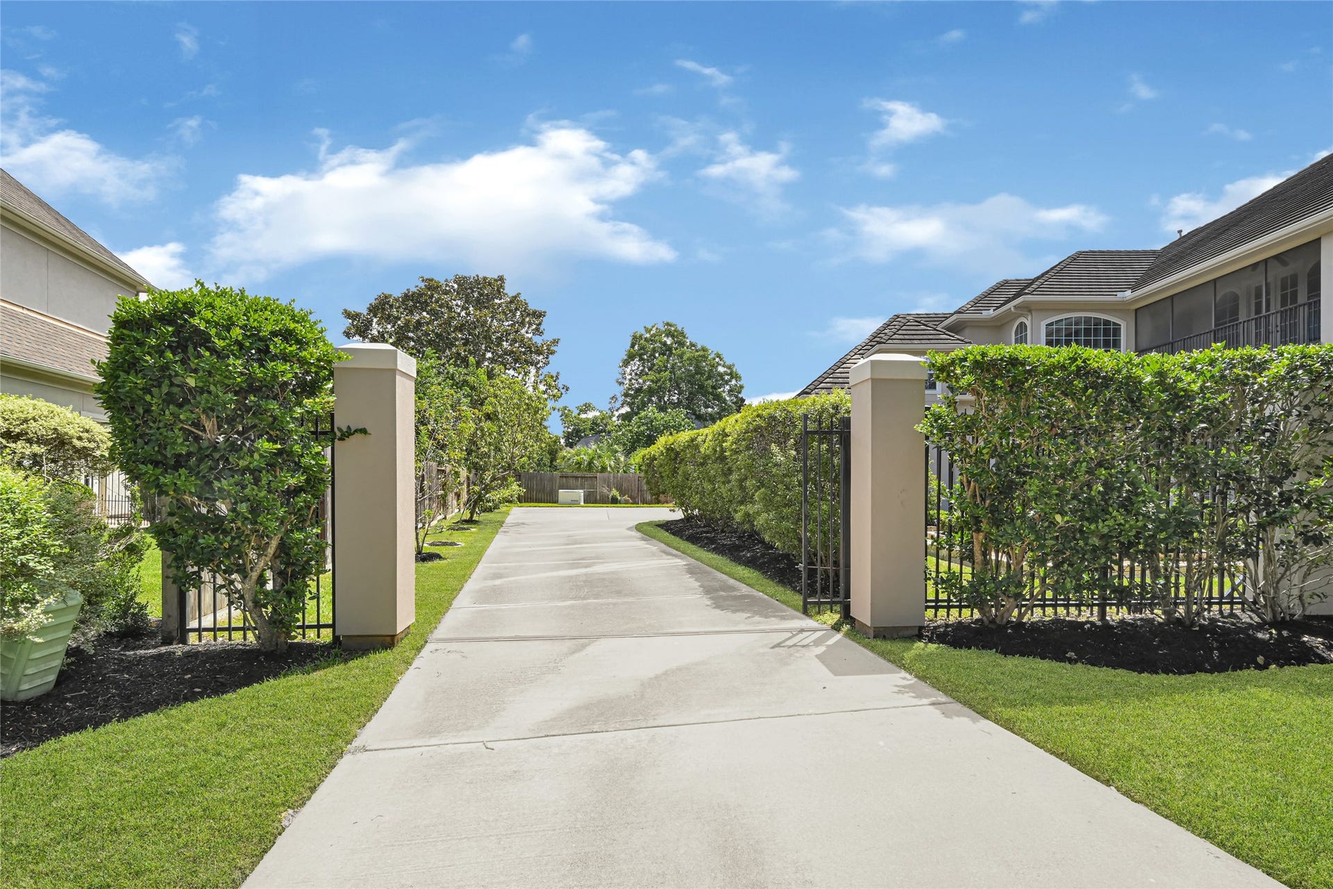 3 Waterford Pointe Circle, Sugar Land, TX 77479 Elegant gated entrance with a long driveway flanked by manicured hedges, leading to a grand property.