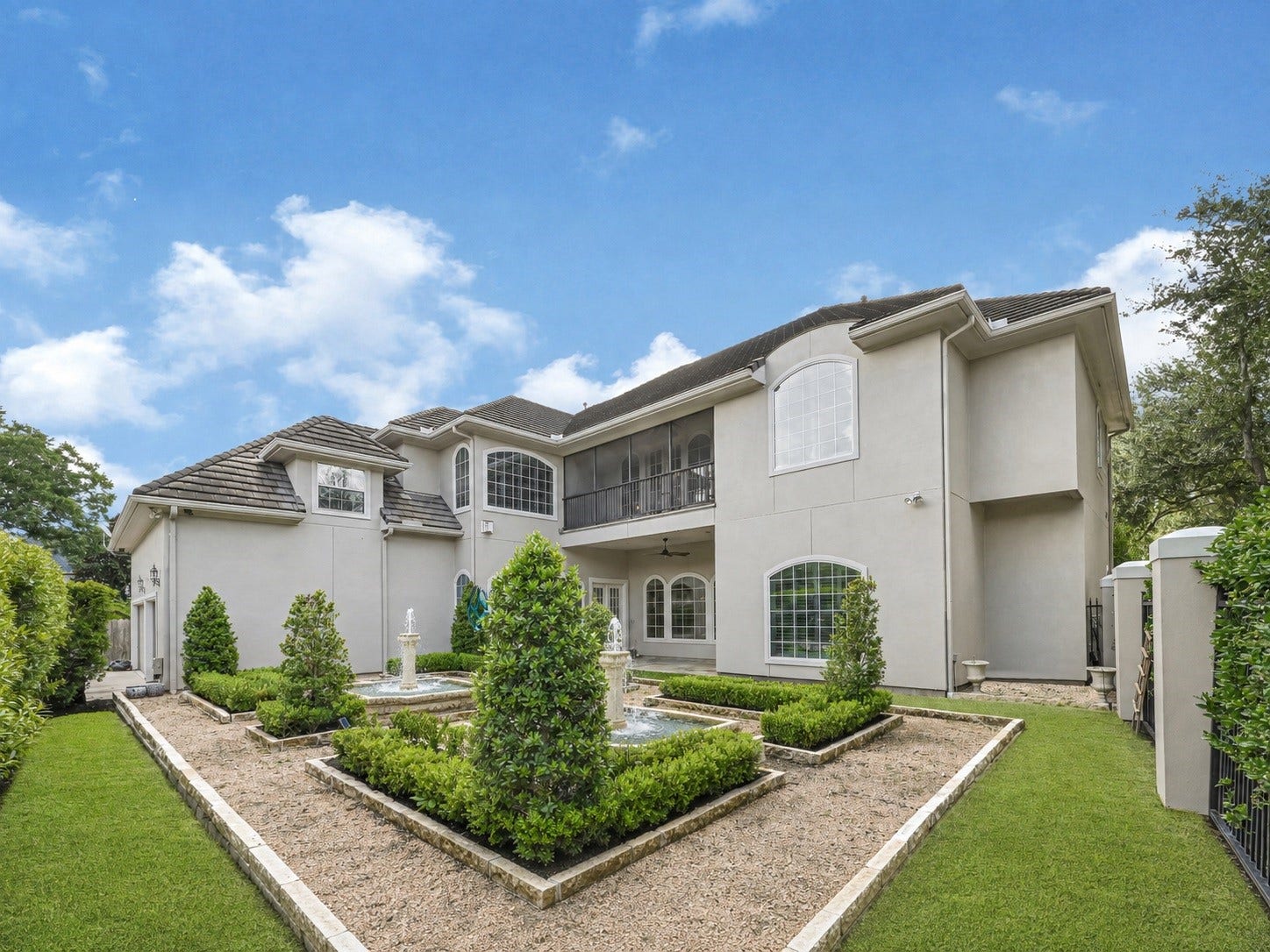 3 Waterford Pointe Circle, Sugar Land, TX 77479 Elegant two-story home with a beautifully manicured garden, featuring a central fountain and lush greenery, exuding luxury and charm.