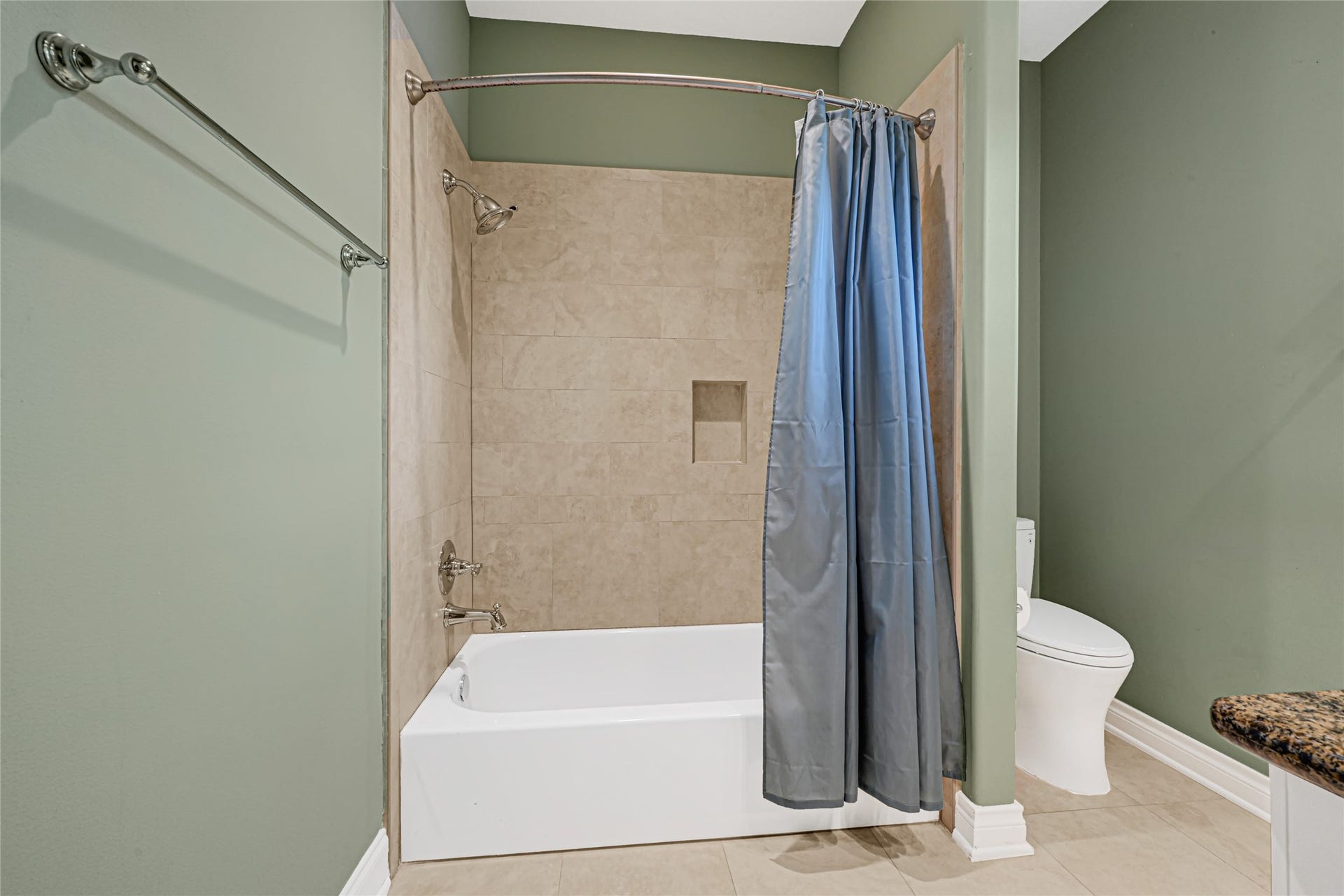 3 Waterford Pointe Circle, Sugar Land, TX 77479 Elegant bathroom featuring a stylish tiled tub and shower combo with a sleek curtain, complemented by soft green walls and modern fixtures.