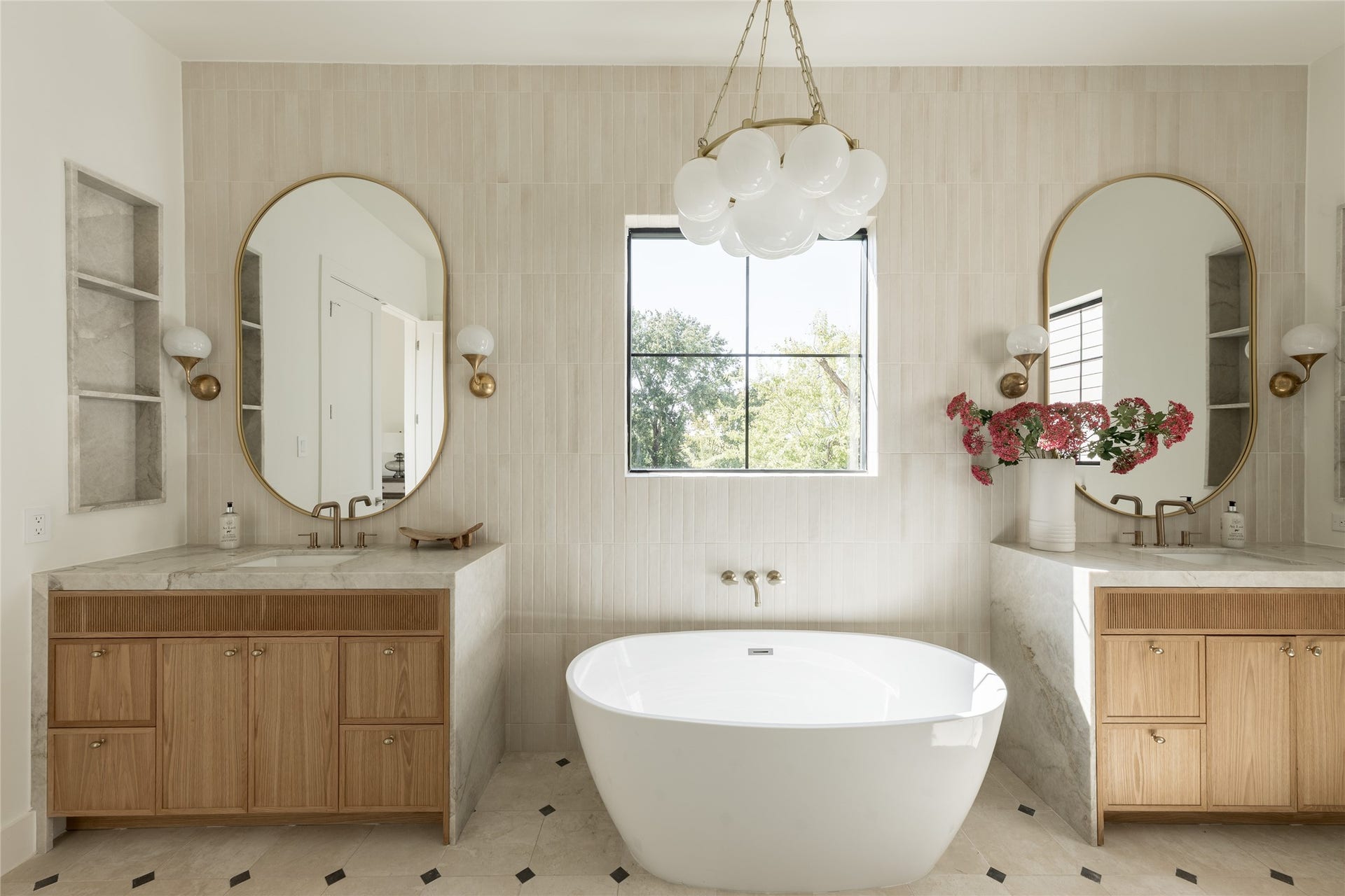 1109 Voight Street, Houston, TX 77009 The spa inspired primary bath centers on a freestanding soaking tub, framed by natural stone, designer tile and sculptural lighting for a quietly dramatic focal point.