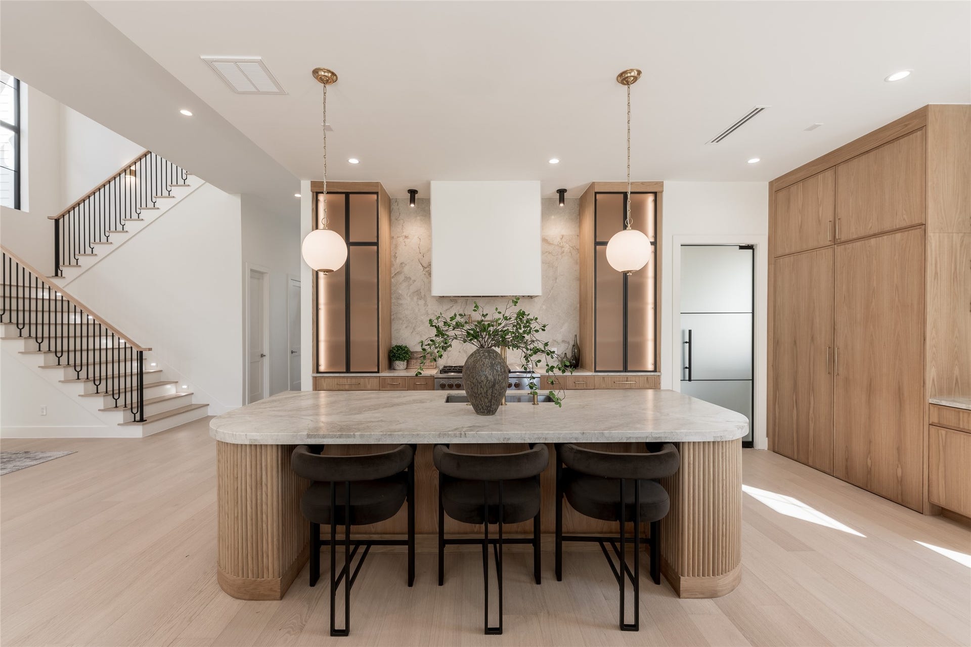 1109 Voight Street, Houston, TX 77009 Thoughtfully layered materials create a kitchen that feels both inviting and architecturally distinctive. The expansive stone-topped island anchors the space, complemented by custom white oak cabinetry, softly illuminated displays, and elegant pendant lighting that balances warmth with contemporary design.