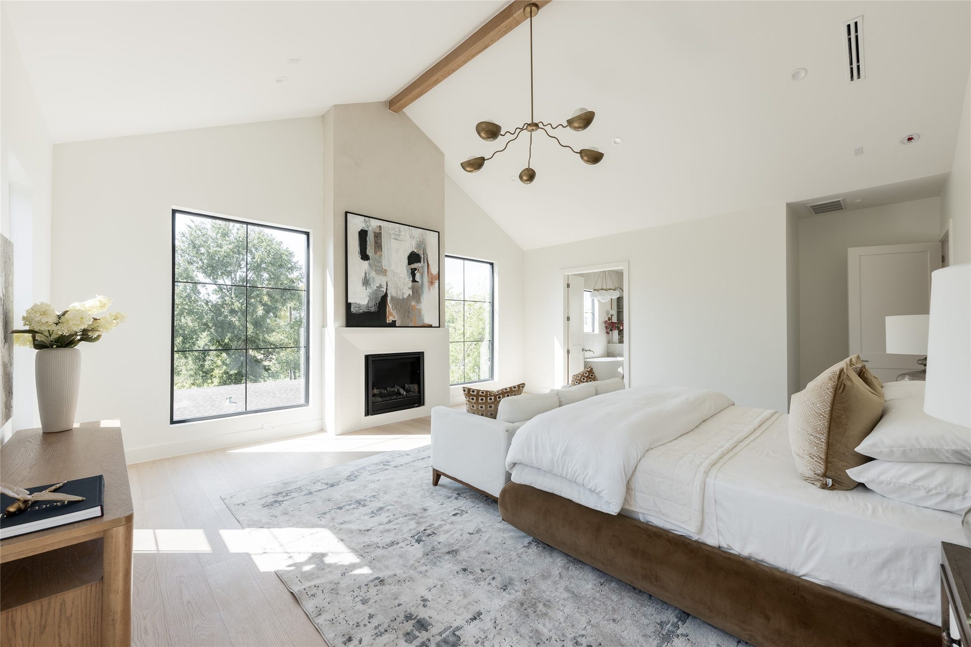 1109 Voight Street, Houston, TX 77009 A first glimpse into the primary retreat, where dramatic ceiling heights meet understated sophistication. Natural light, warm wood accents, and a private sitting area establish a calming atmosphere, offering an early look at one of the home's most inviting spaces.