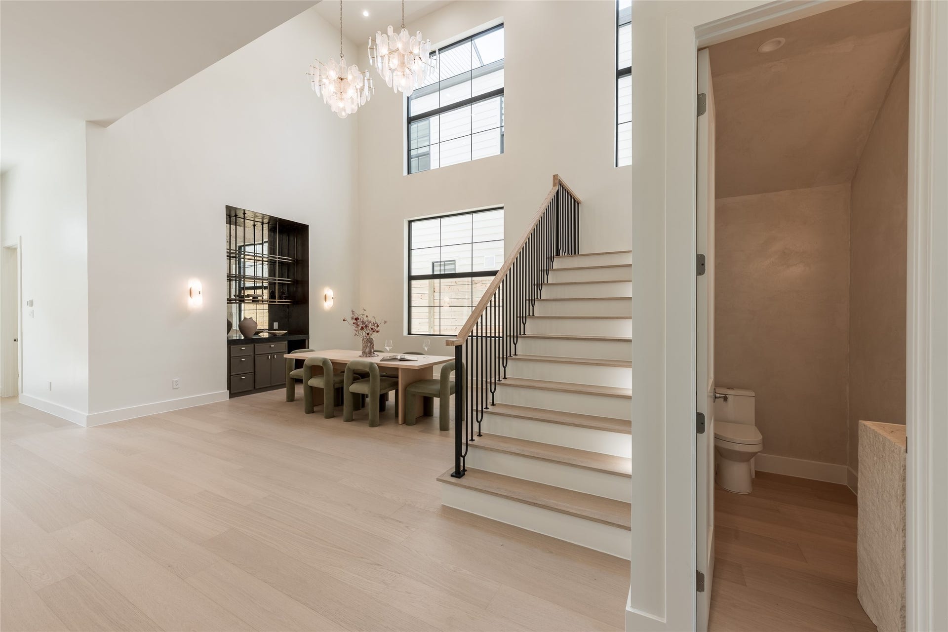 1109 Voight Street, Houston, TX 77009 The two-story dining room makes a striking statement with soaring ceilings, cascading chandeliers, and expansive windows. An integrated bar adds sophistication, creating an inviting setting for intimate dinners and entertaining.