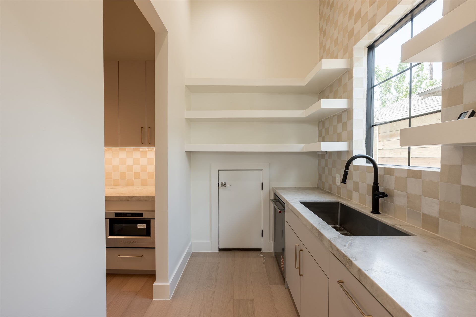 1109 Voight Street, Houston, TX 77009 The scullery is designed for more than extra prep and storage, with a dedicated grocery pass through connecting directly from the garage for effortless unloading. Open shelving, natural stone counters and a secondary sink keep everyday function beautifully out of sight.