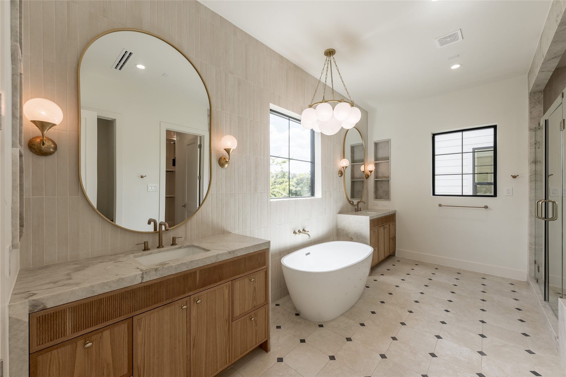 1109 Voight Street, Houston, TX 77009 A wide perspective of the primary bath reveals thoughtful symmetry, pairing dual vanities with a freestanding soaking tub and natural stone surfaces. Designer tile carries across the floor and walls, giving the ensuite a tailored, cohesive finish.
