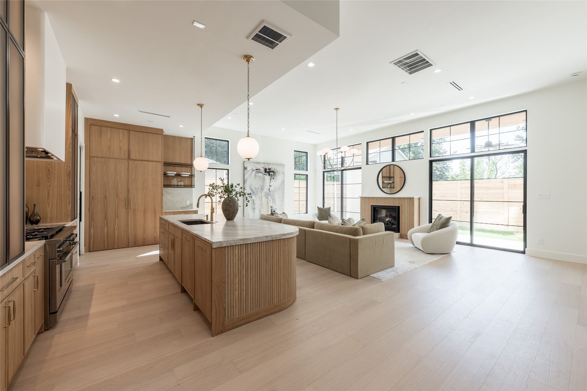 1109 Voight Street, Houston, TX 77009 Integrated cabinet lighting highlights the custom white oak cabinetry and sculptural hood, while the kitchens open exposure to the soaring dining room creates a striking visual connection between the two spaces.