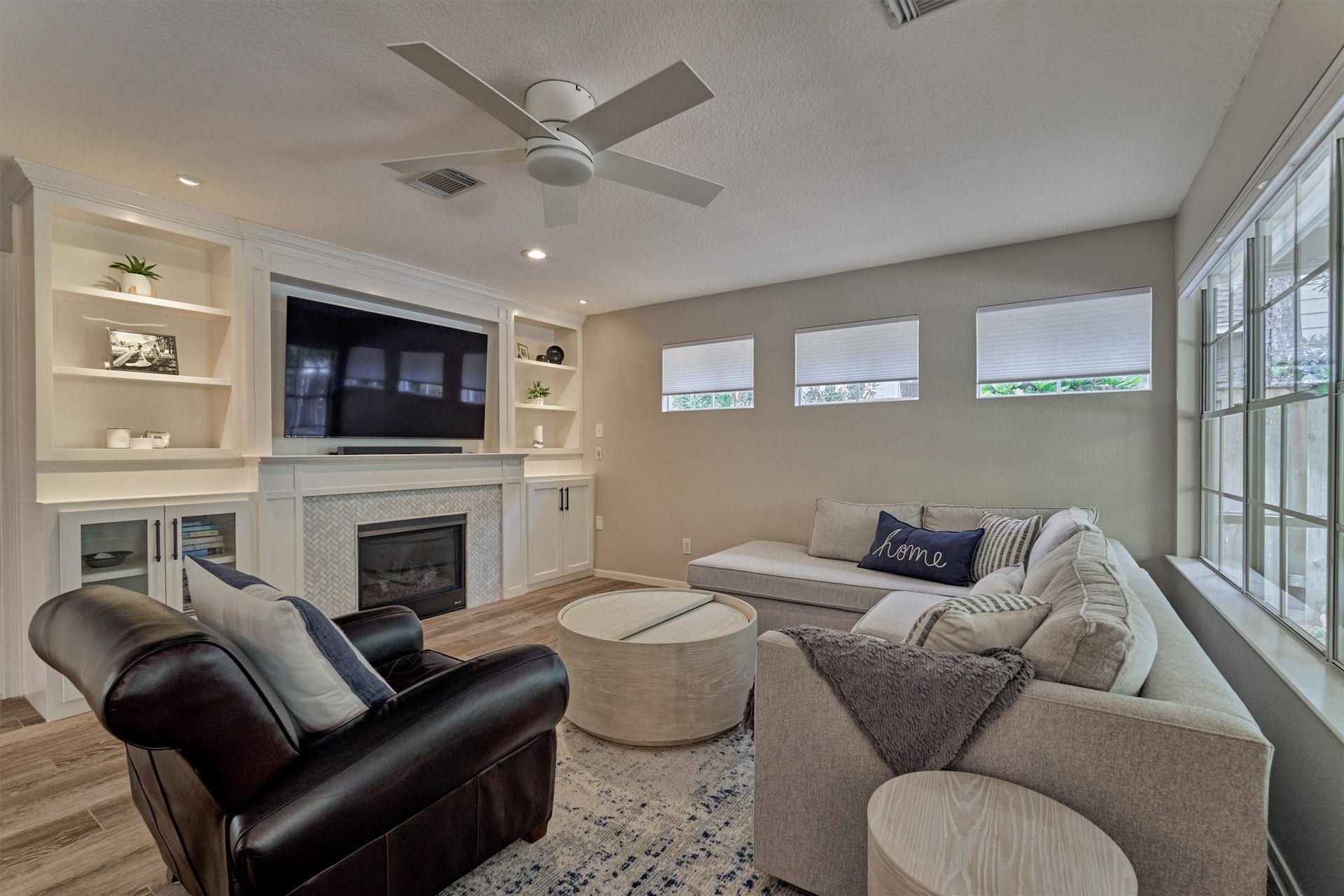 Cozy den featuring beautifully updated cabinetry flanking the fireplace creates an inviting space to gather and unwind.