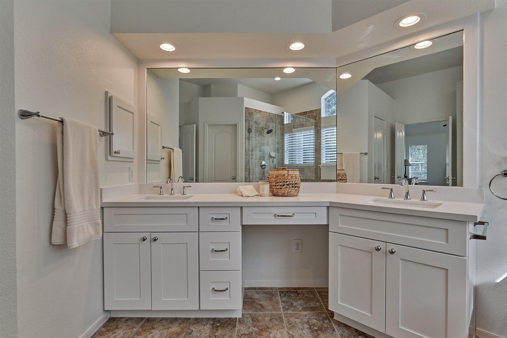 Dual sinks and a dedicated vanity area complement the light, bright countertops and cabinetry, creating a fresh and inviting space.
