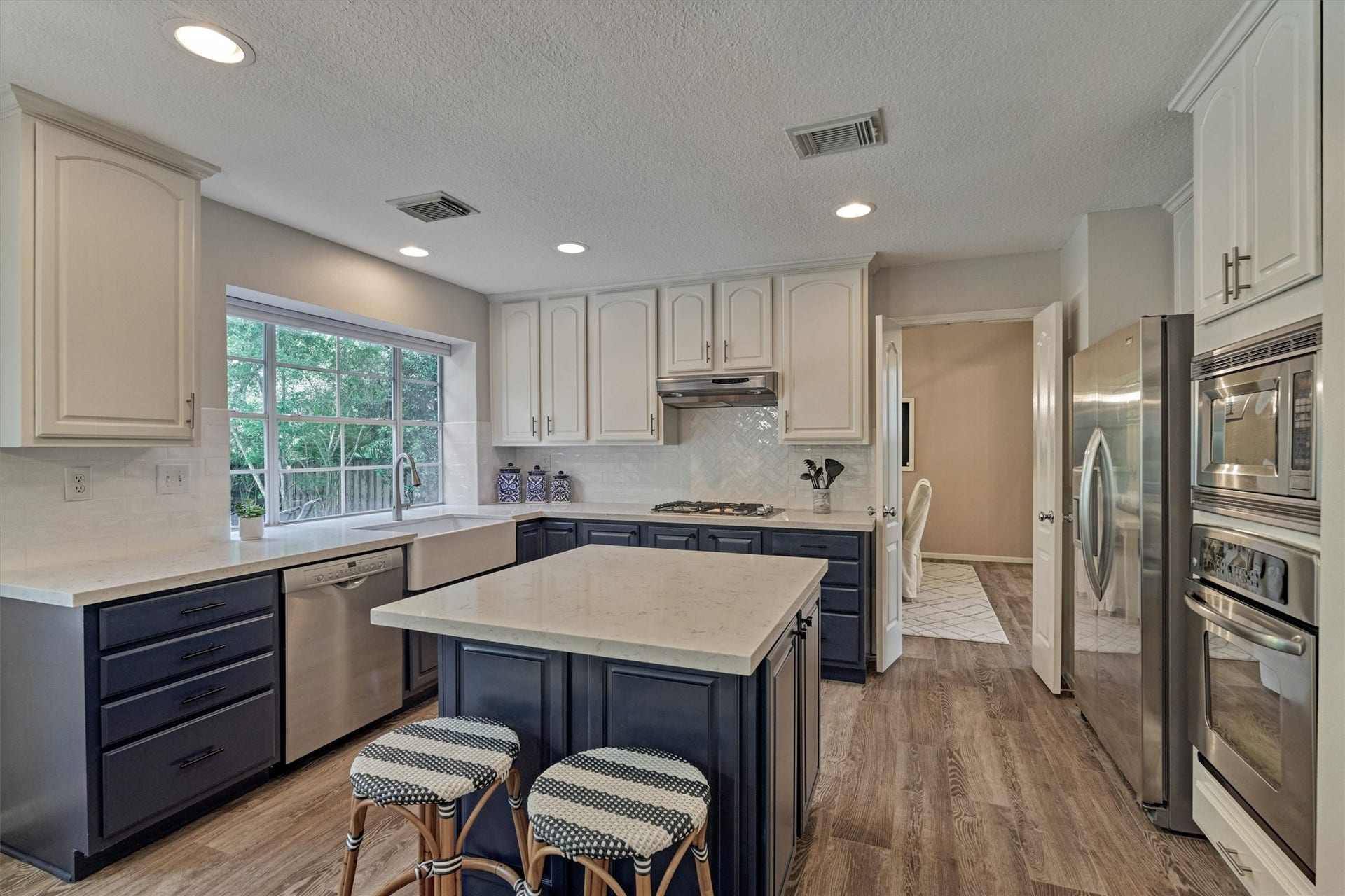Designer kitchen showcases quartz countertops beautifully contrasted by rich blue lower cabinetry!