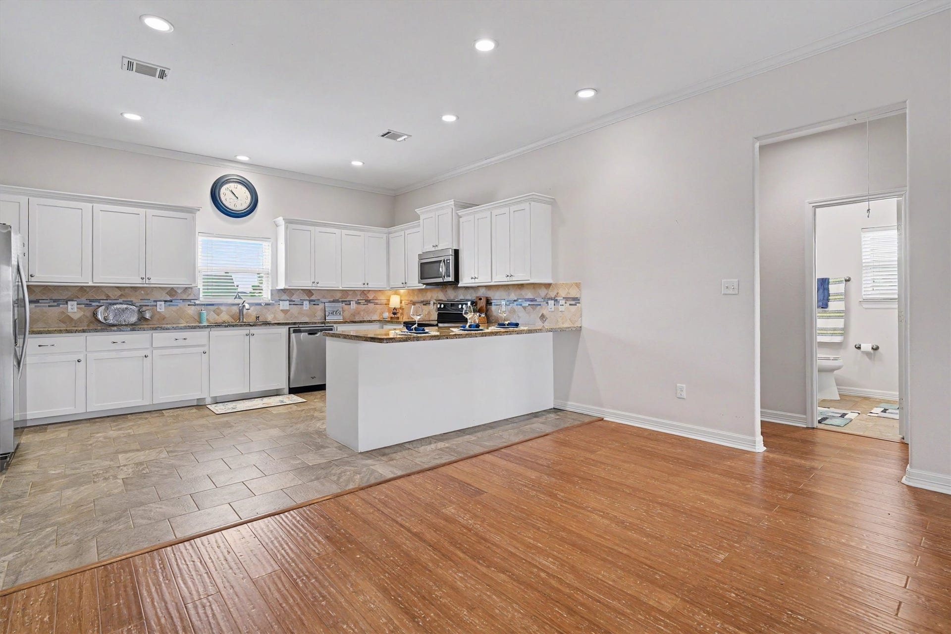 437 Pompano Street, Bayou Vista, TX 77563 The coastal-inspired white kitchen radiates elegance and charm, featuring sleek cabinetry and modern appliances. At the heart of this space is a large peninsula breakfast bar, perfect for casual dining or entertaining guests