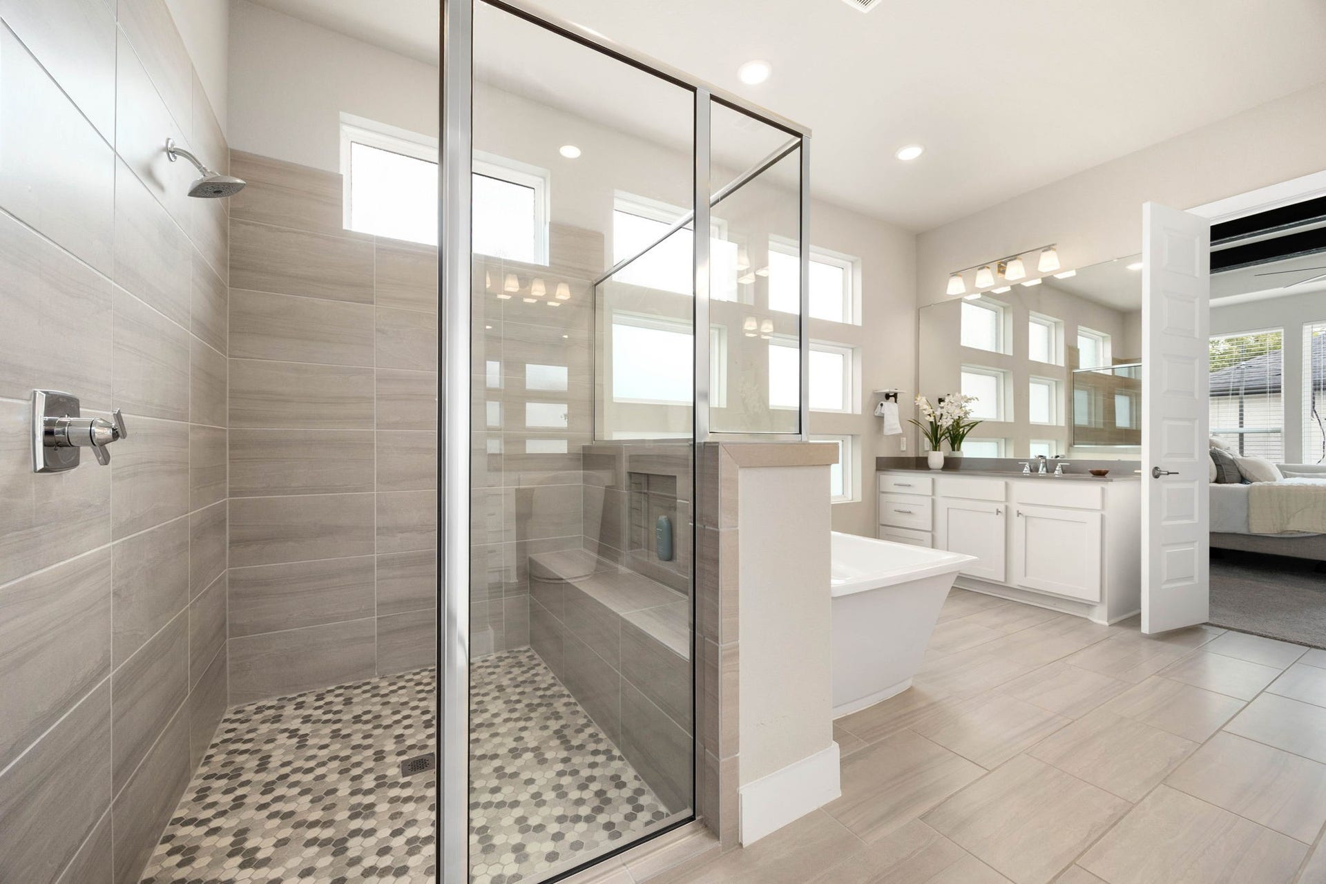 Oversized walk-in shower with frameless glass, bench seating and elegant tile finishes.