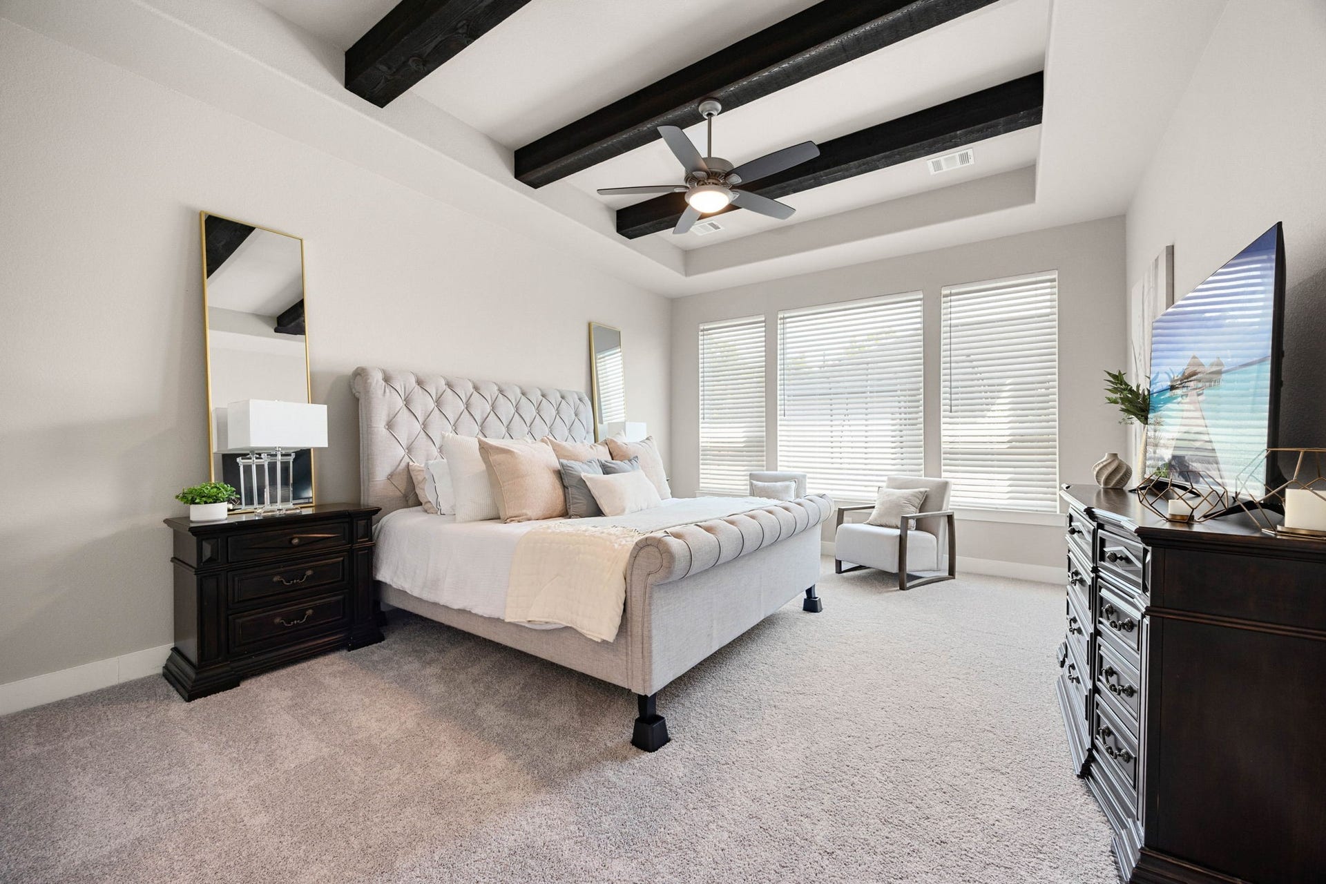 Generous primary suite with a tray ceiling, decorative beams and a peaceful connection to the ensuite bath.
