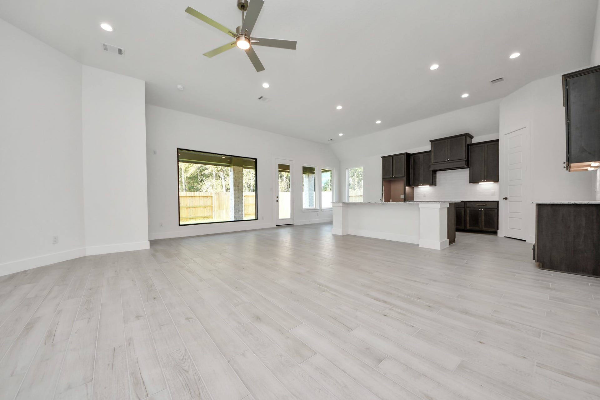 Welcome family and guests to your charming living room! With its high ceilings, recessed lighting, ceiling fan, custom paint, beautiful flooring, and large windows that let in abundant natural light, this room is perfect for gatherings.