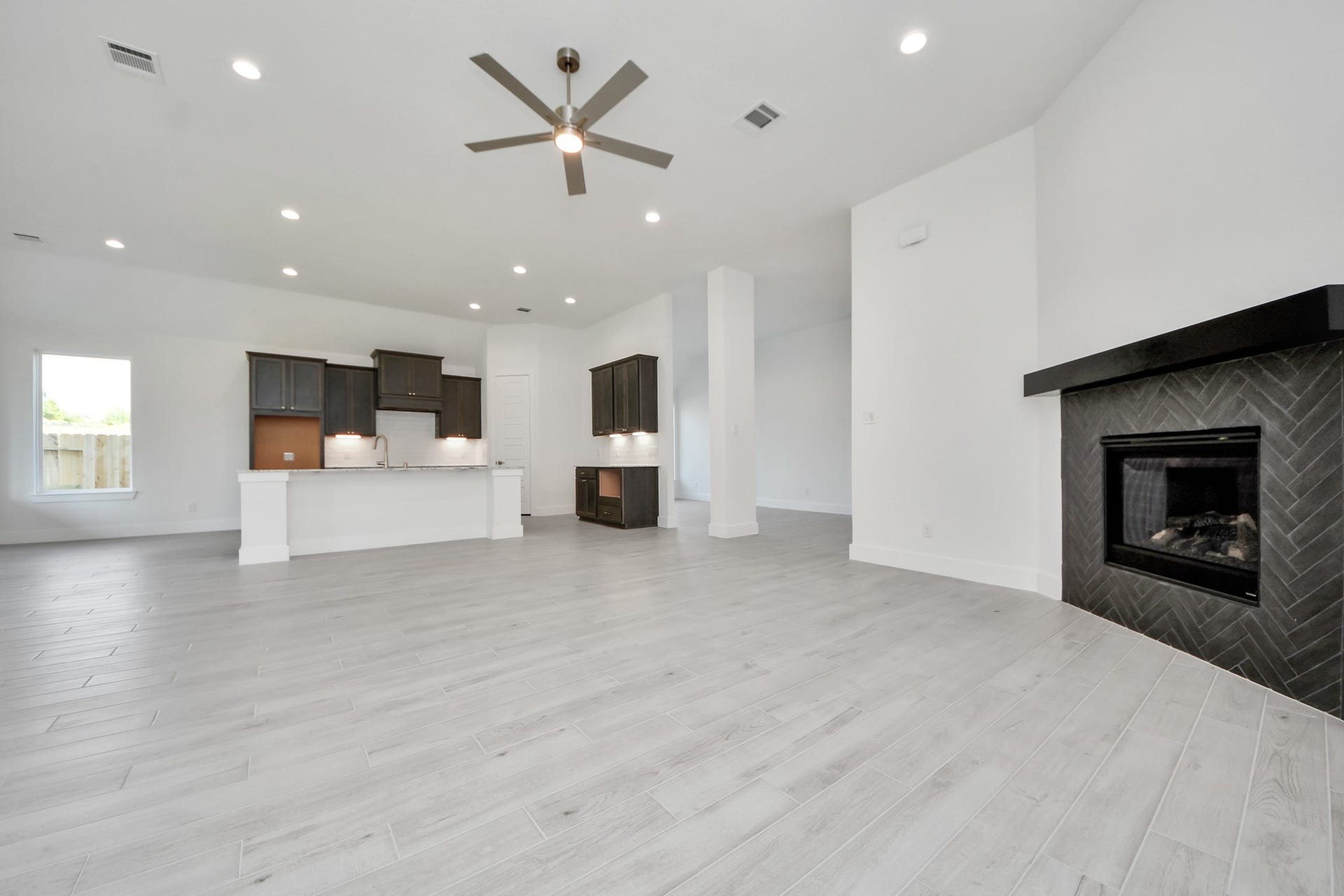 Relax and unwind in this inviting family room, illuminated by abundant natural light streaming in through tall windows, complemented by high ceilings and stunning flooring. Stay comfortable year-round with the gentle breeze from the ceiling fan, creating the perfect atmosphere for family gatherings.