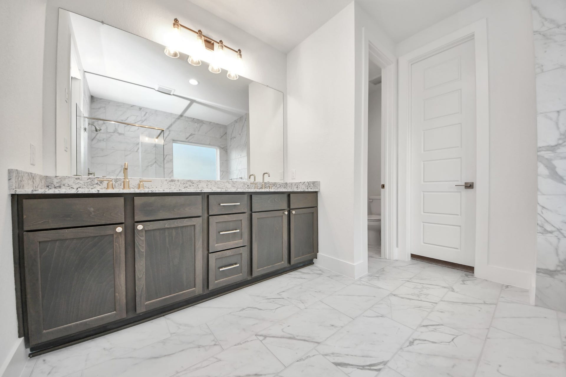 Escape to a spa-like oasis in this primary bathroom. Enjoy a walk-in shower with tile surround, a separate garden tub with custom detailing, and an elegant vanity featuring light countertops, modern hardware, and beautiful vanity lights. Experience luxury and relaxation in every detail.