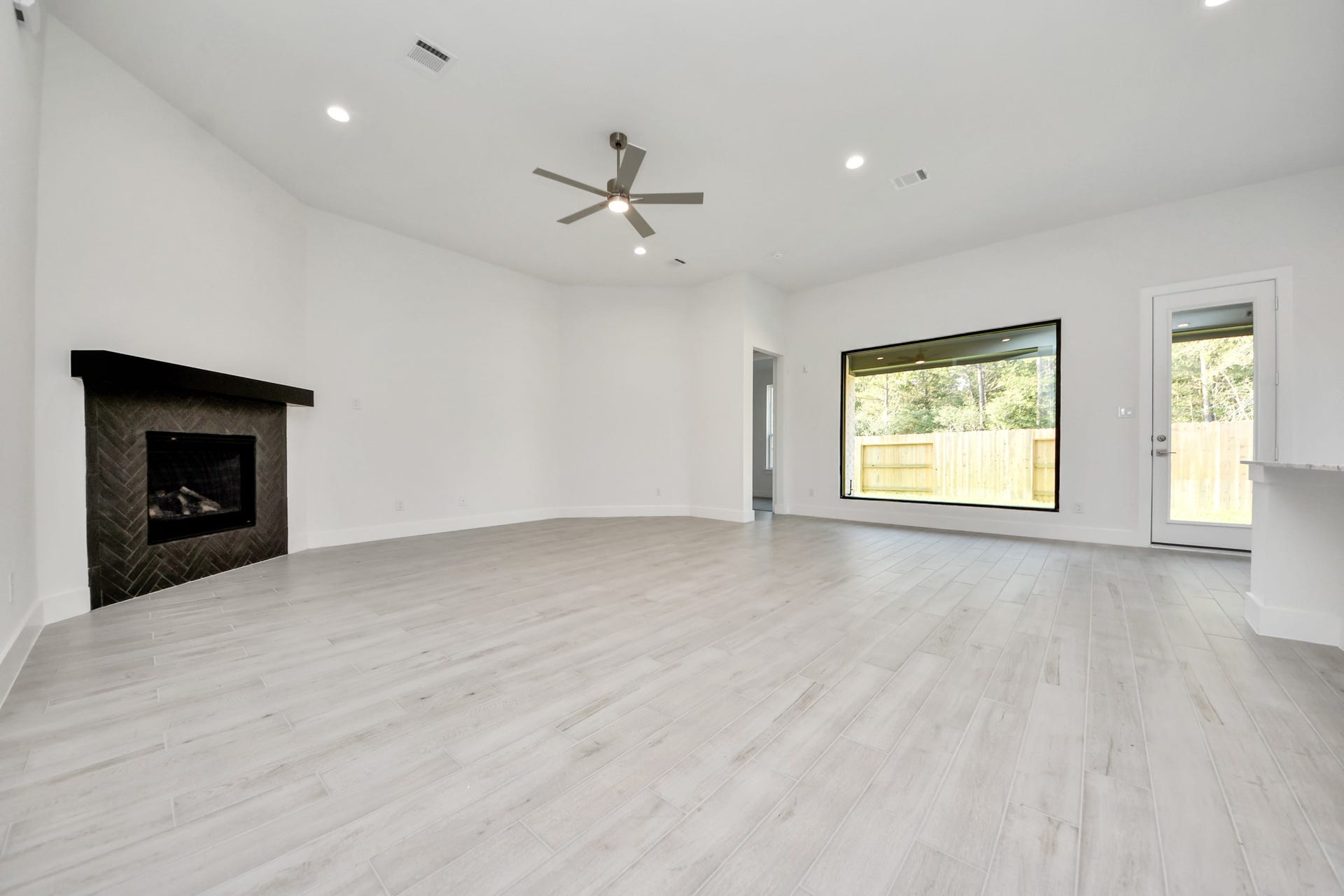 Family room flooded with natural light through the expansive windows.  The premium tile flooring adds a touch of luxury to the space, creating the perfect setting for relaxing moments and cherished gatherings with loved ones