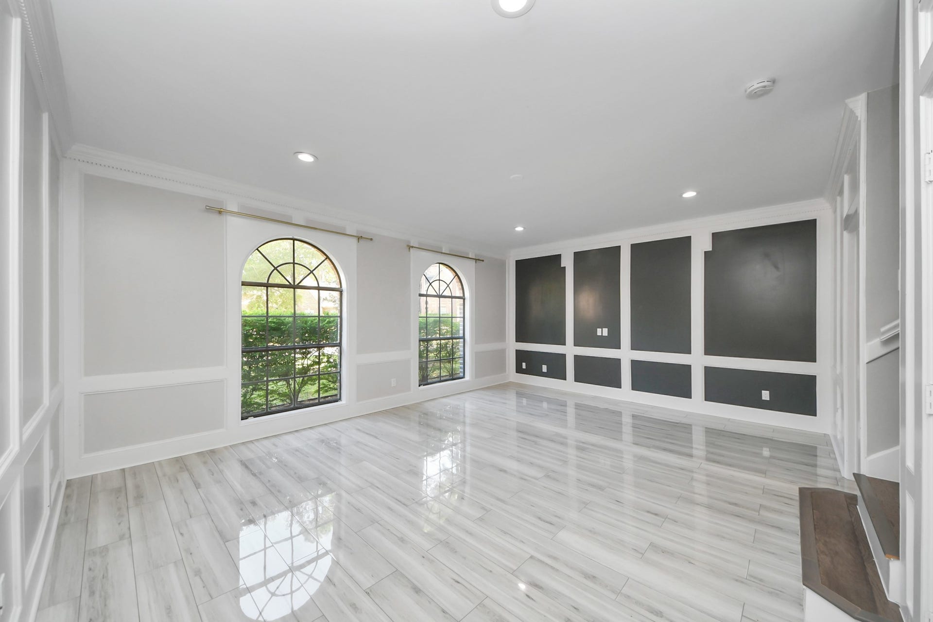 24 Hornsilver Place, The Woodlands, TX 77381 Bright and spacious formal living area featuring elegant arched windows, sleek tile flooring, and modern accent walls.