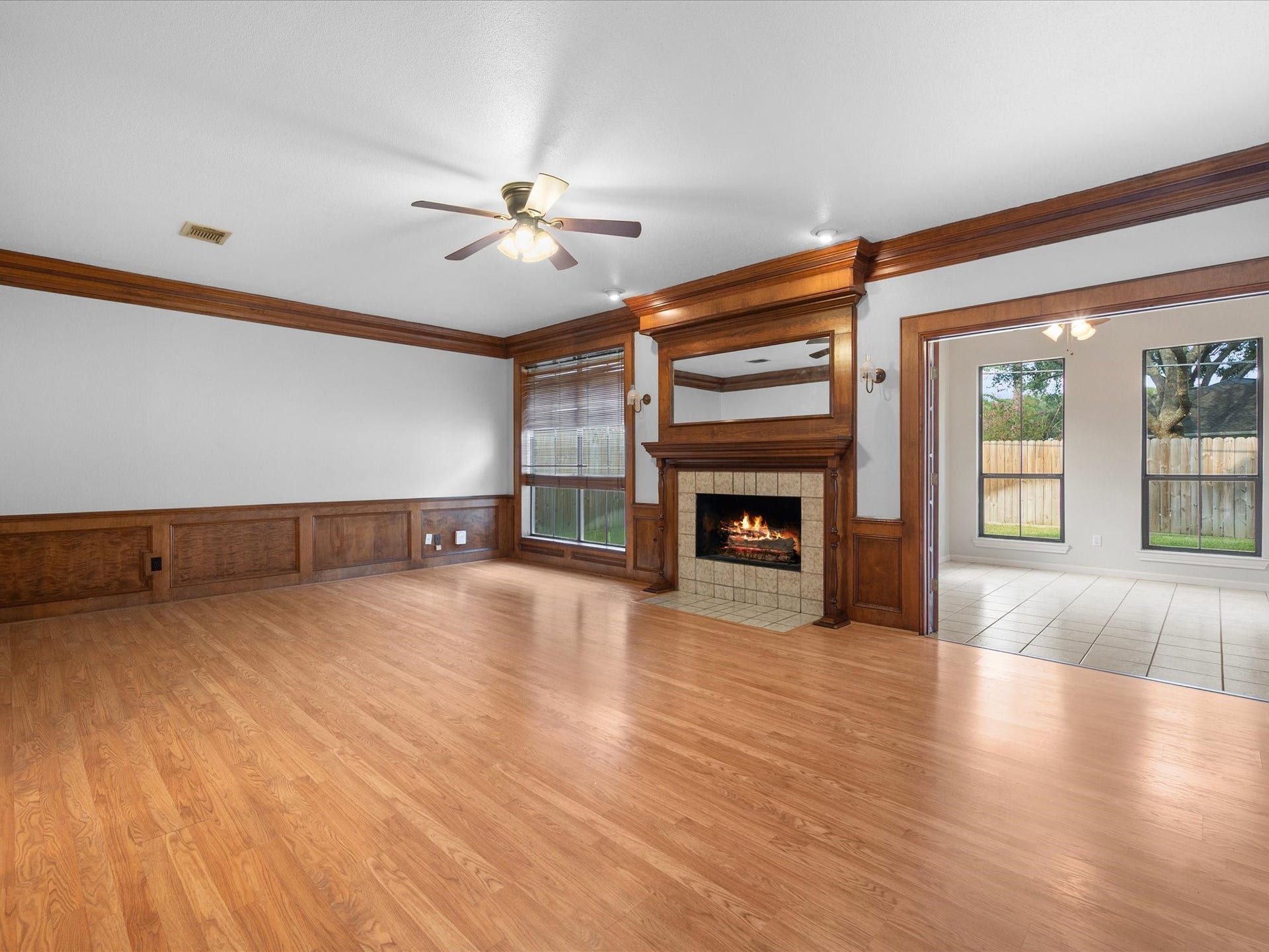 18006 Memorial Estates Drive, Spring, TX 77379 The living room has wood floors, crown molding, and a gas log fireplace. A ceiling fan and big windows keep it bright.
