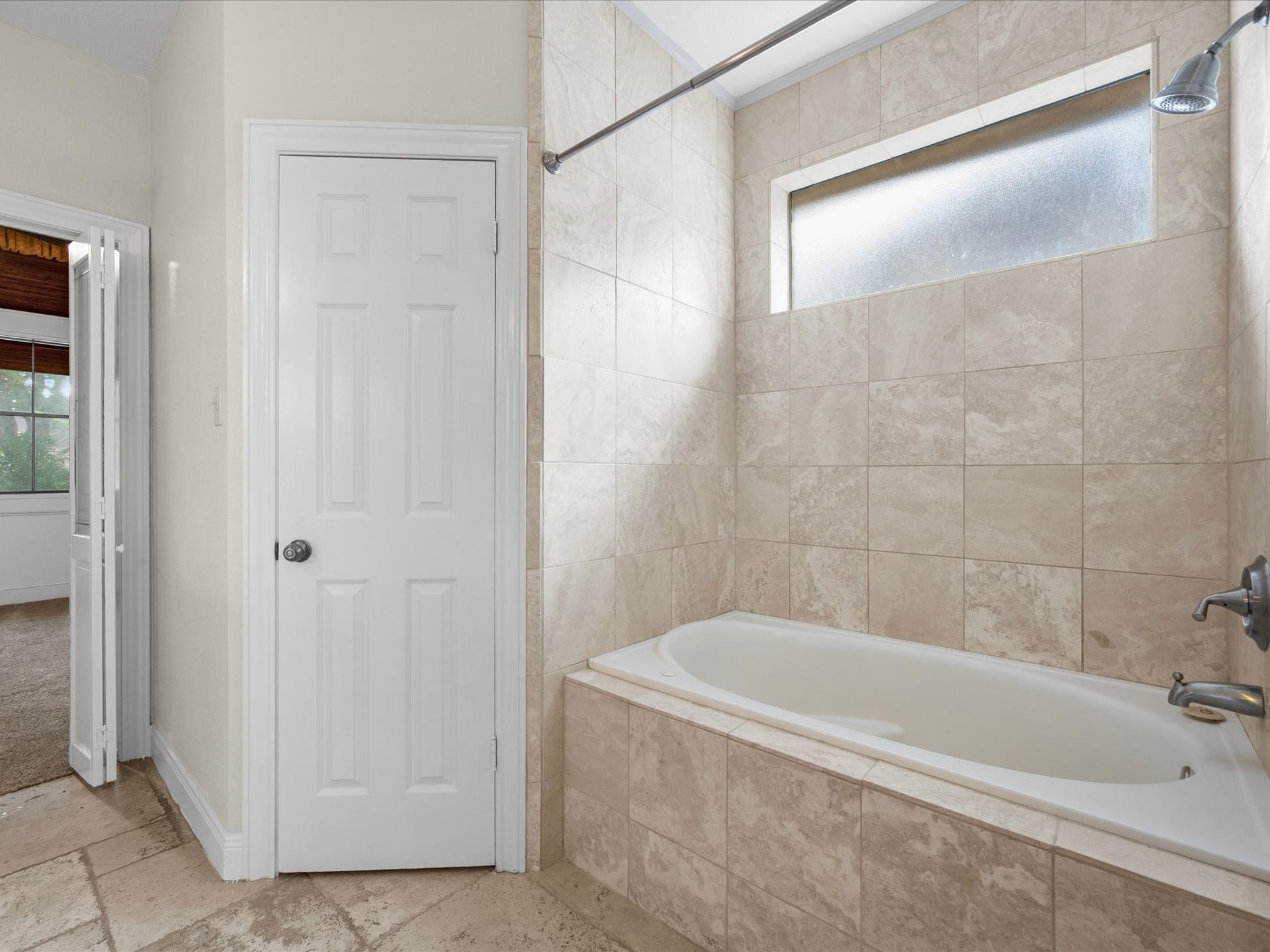 18006 Memorial Estates Drive, Spring, TX 77379 The soaking tub in the primary bath is surrounded by tile, with a window above.