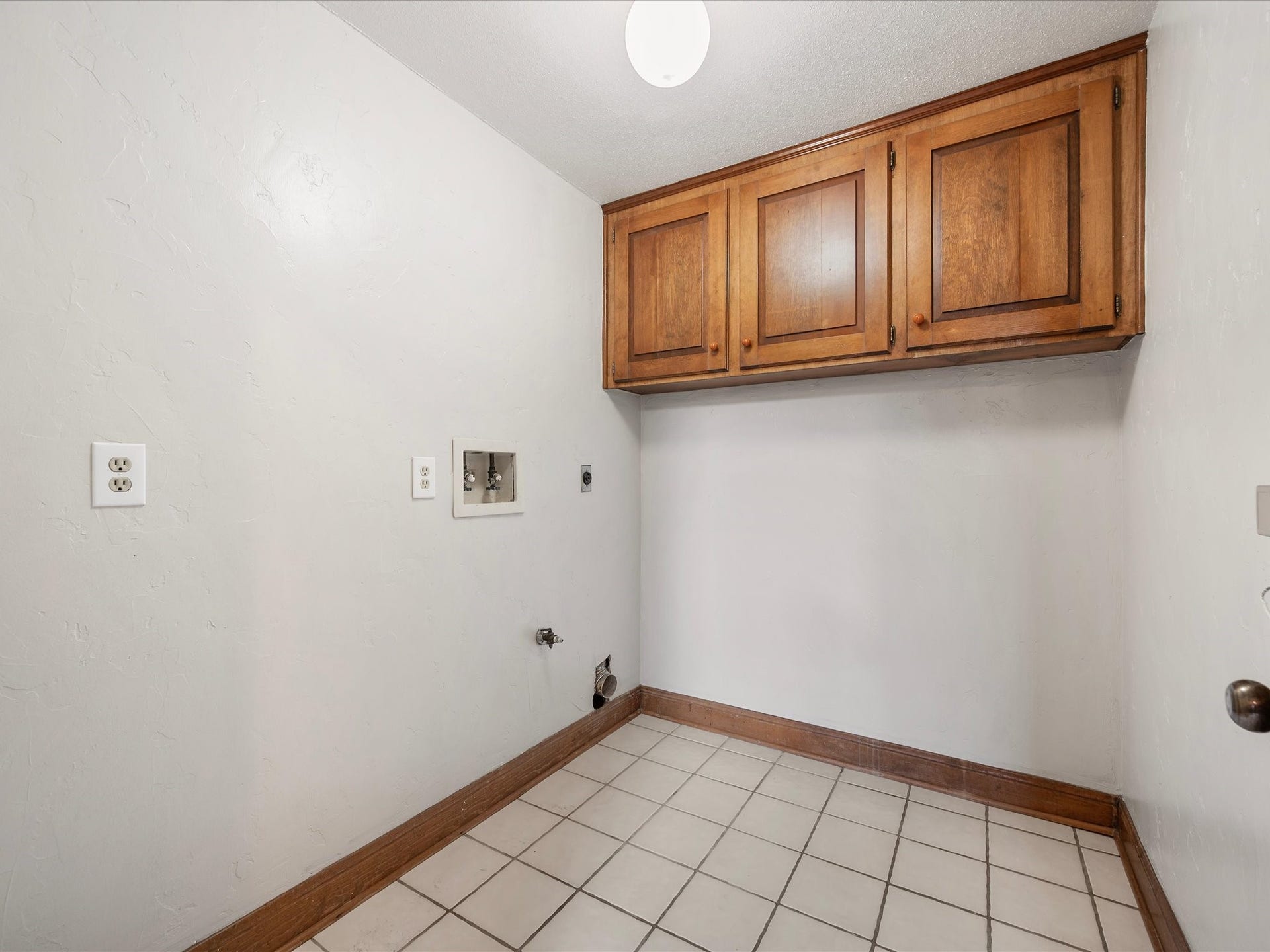 18006 Memorial Estates Drive, Spring, TX 77379 The laundry room is inside the house, with cabinets above and tile floors.