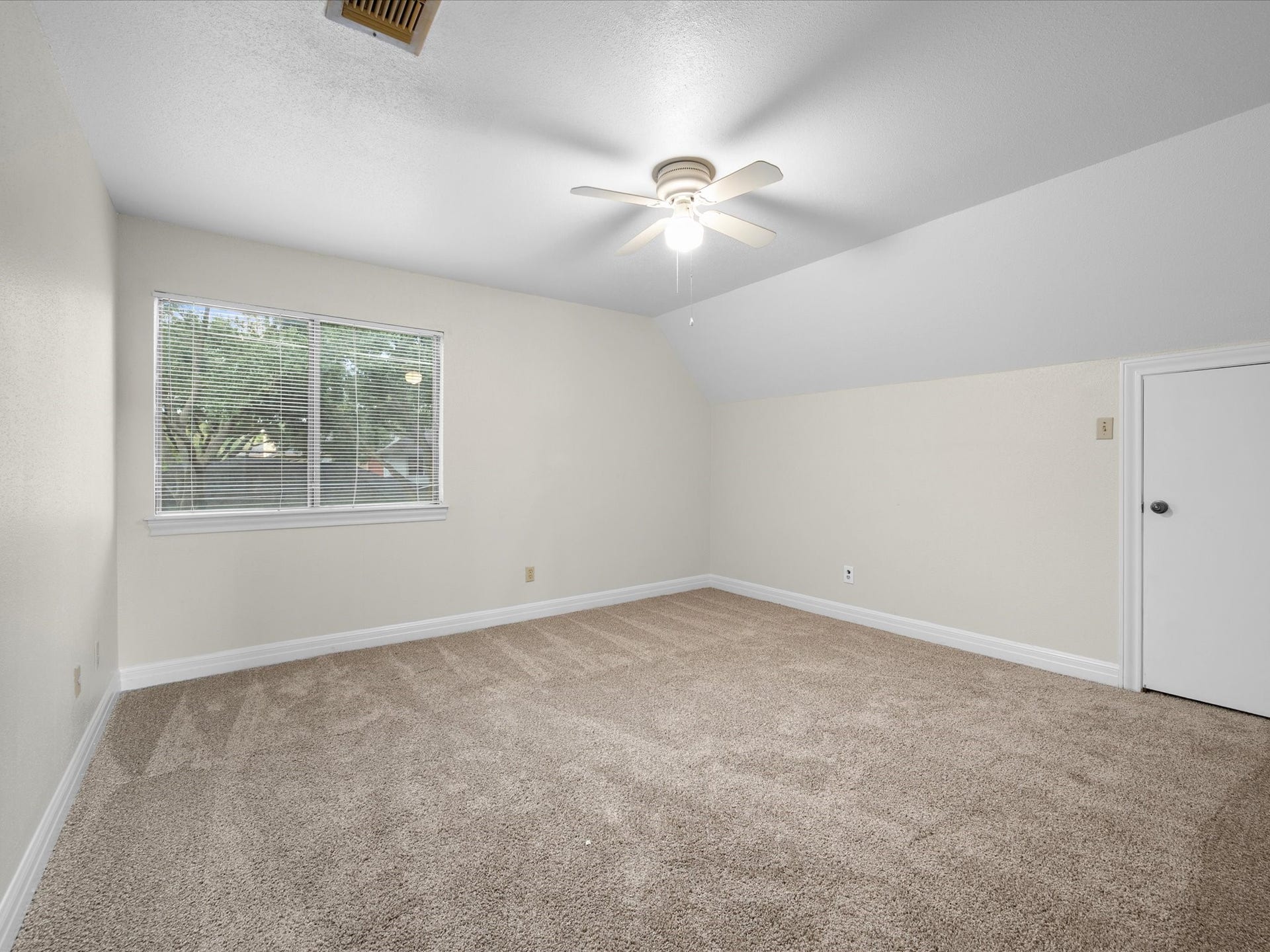 18006 Memorial Estates Drive, Spring, TX 77379 Upstairs bedroom with new carpet, a sloped ceiling, a ceiling fan, and a view of the trees.