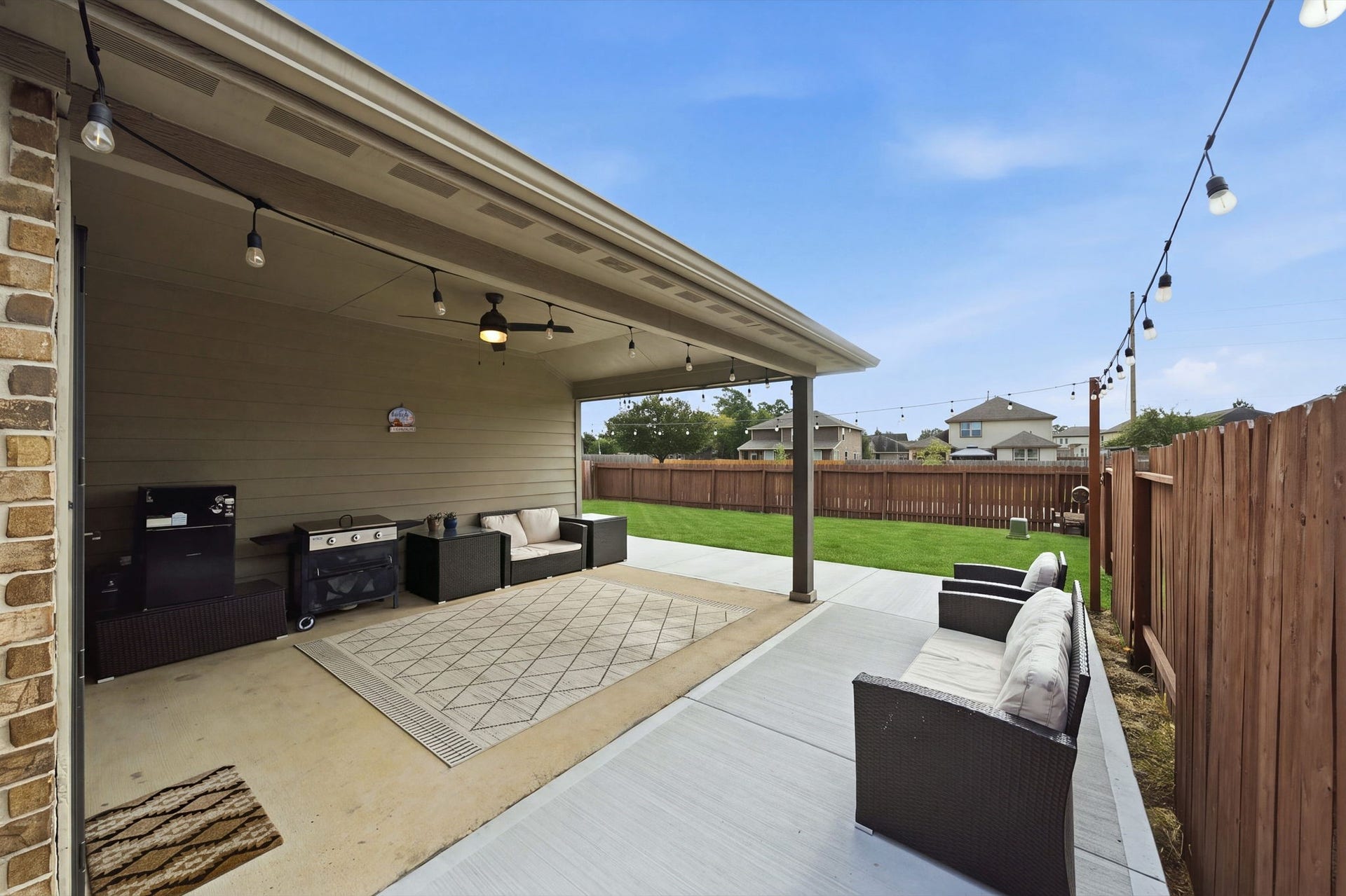 336 Country Crossing Circle, Magnolia, TX 77354 Charming covered patio with comfortable seating, perfect for entertaining, opens up to a spacious fenced backyard with lush greenery.