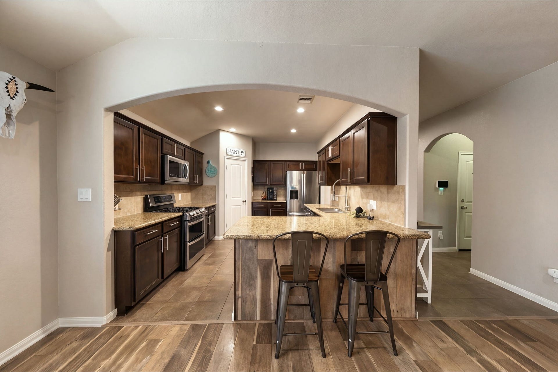 336 Country Crossing Circle, Magnolia, TX 77354 Spacious kitchen with rich wood cabinetry, granite countertops, and a central island with seating, complemented by stainless steel appliances and a cozy pantry nook.