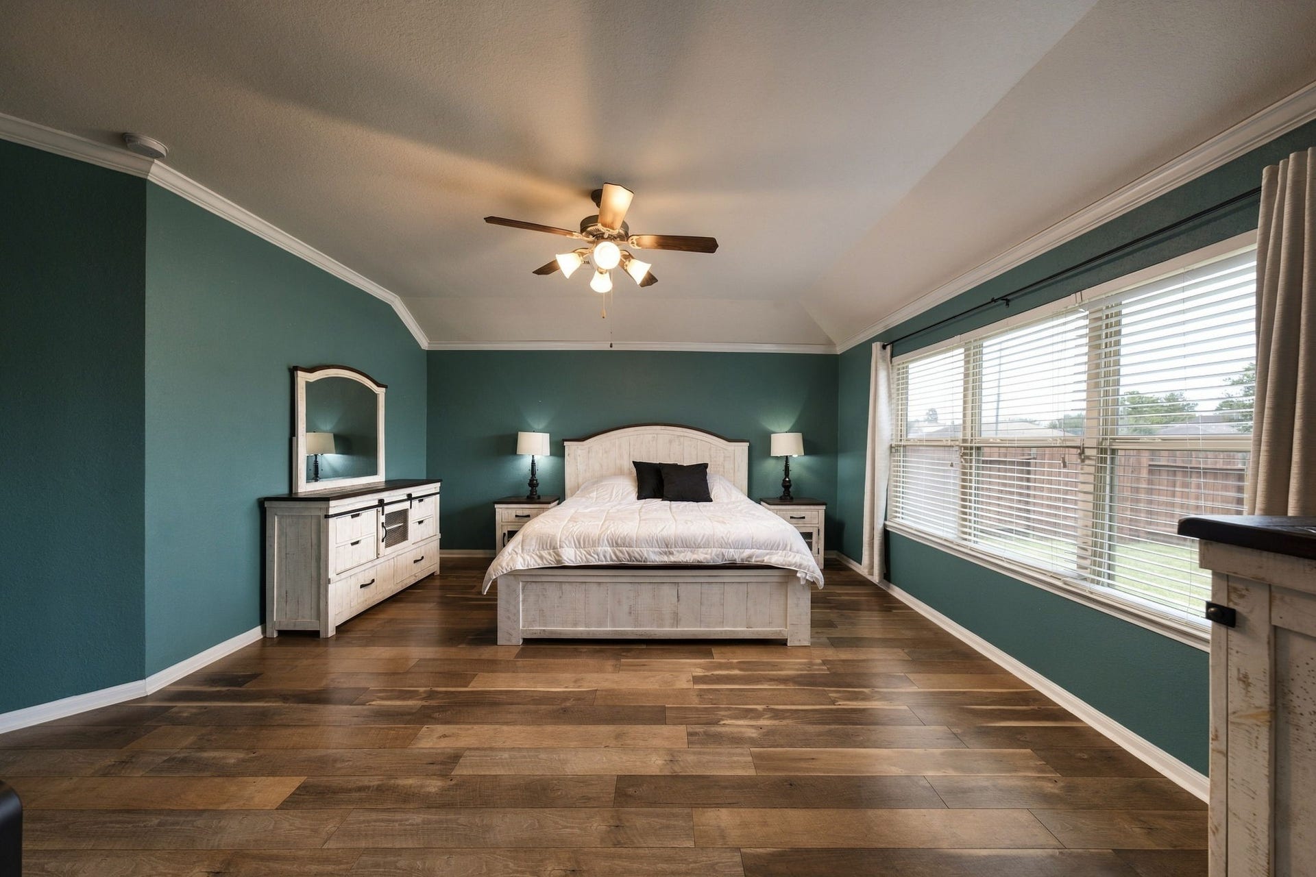 336 Country Crossing Circle, Magnolia, TX 77354 Spacious bedroom featuring rich wooden flooring, a large window for natural light, and elegant teal walls complemented by classic white.