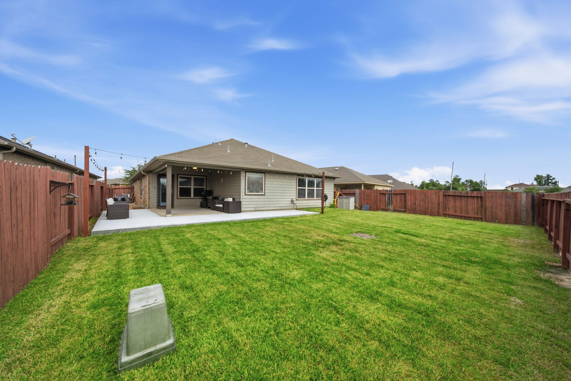 336 Country Crossing Circle, Magnolia, TX 77354 Spacious backyard with a well-maintained lawn, featuring a cozy covered patio perfect for outdoor gatherings, all enclosed by a charming wooden fence.