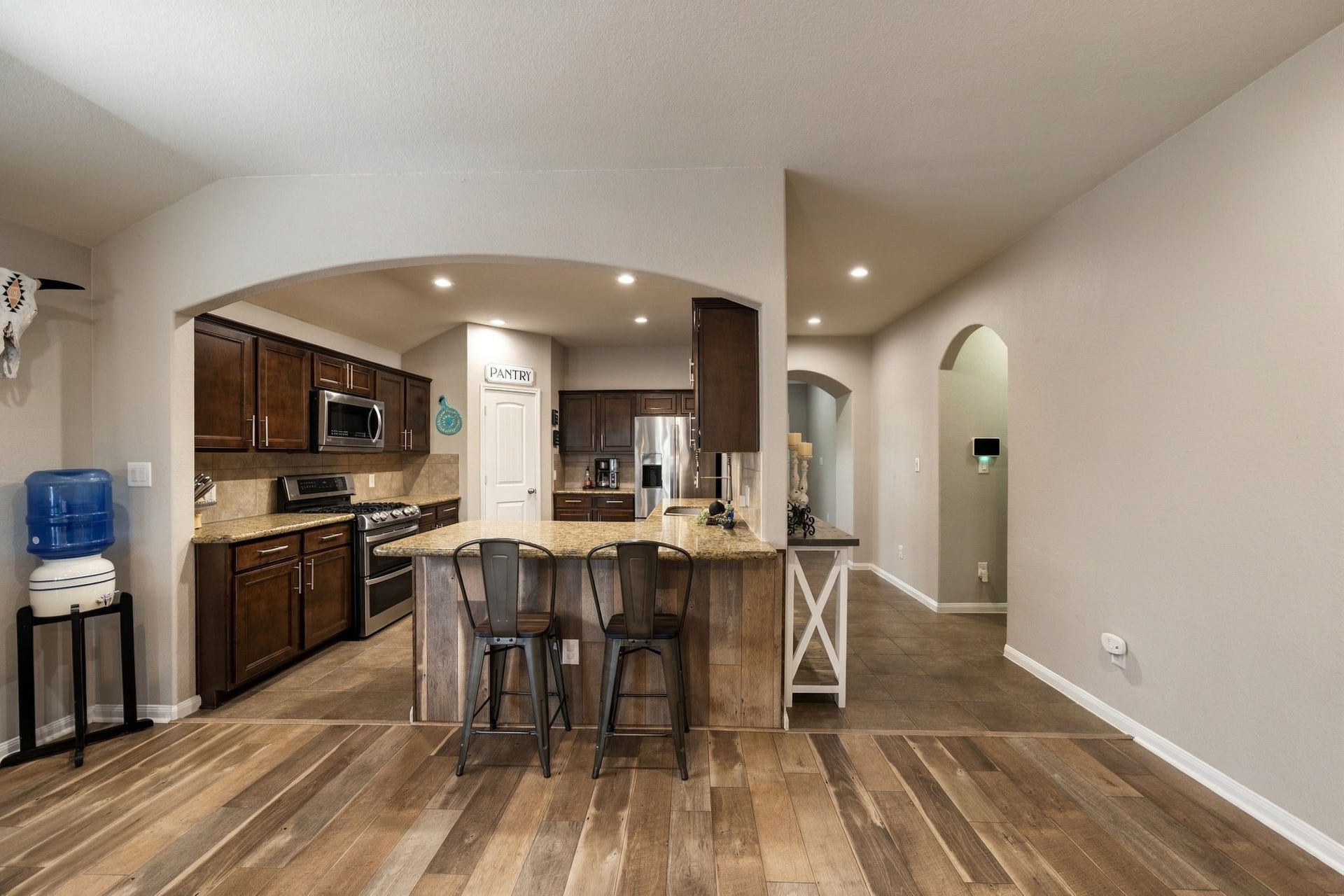 336 Country Crossing Circle, Magnolia, TX 77354 Charming kitchen with rich wood cabinetry, stainless steel appliances, and a cozy breakfast bar under a graceful archway.